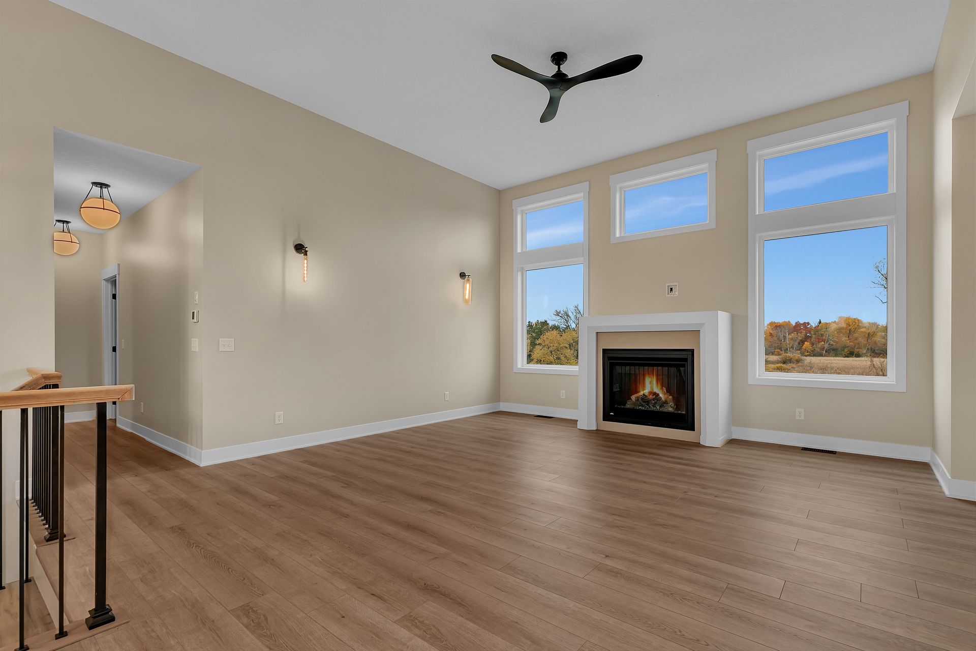 An empty living room with a fireplace and a ceiling fan.