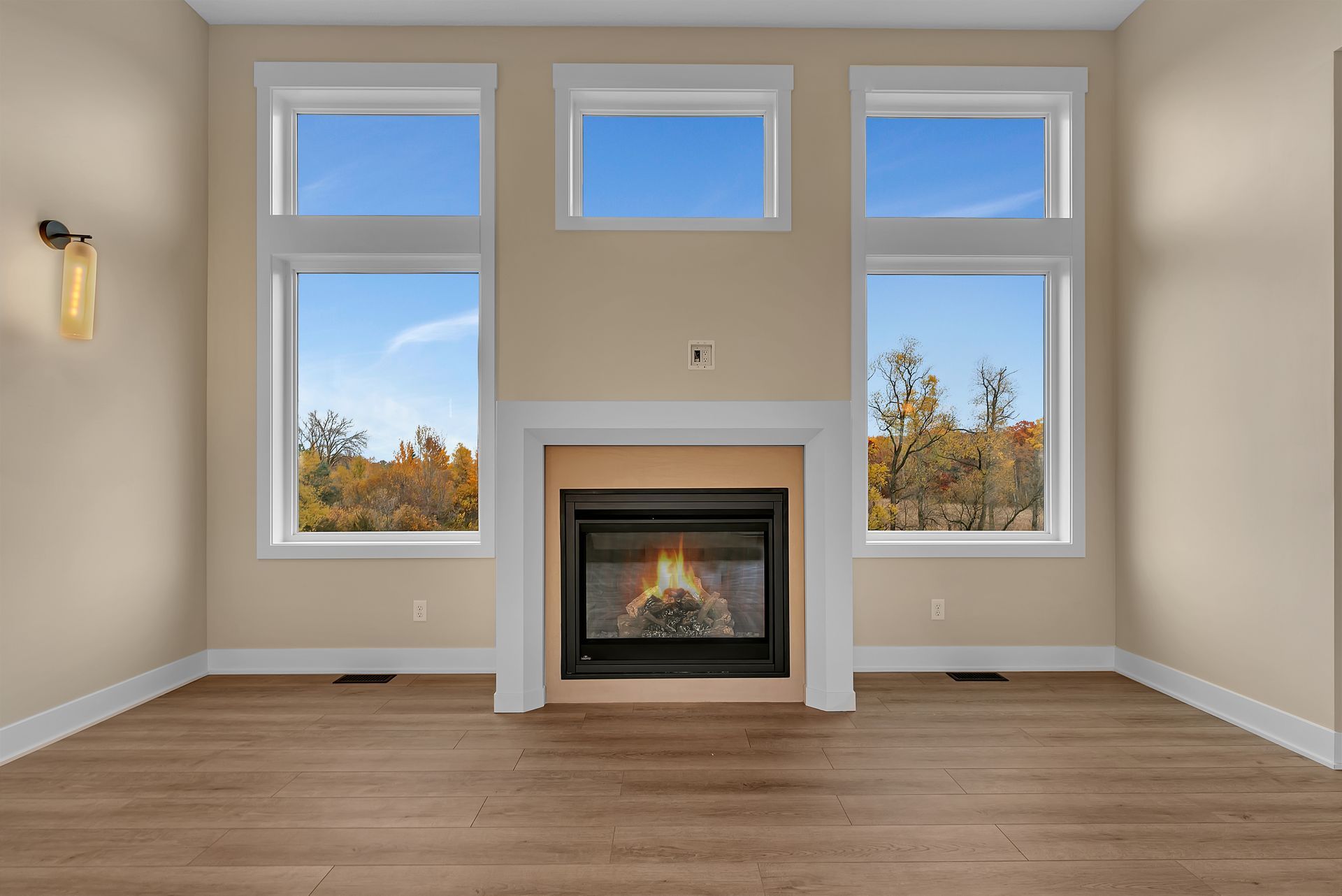 An empty living room with a fireplace and two windows.