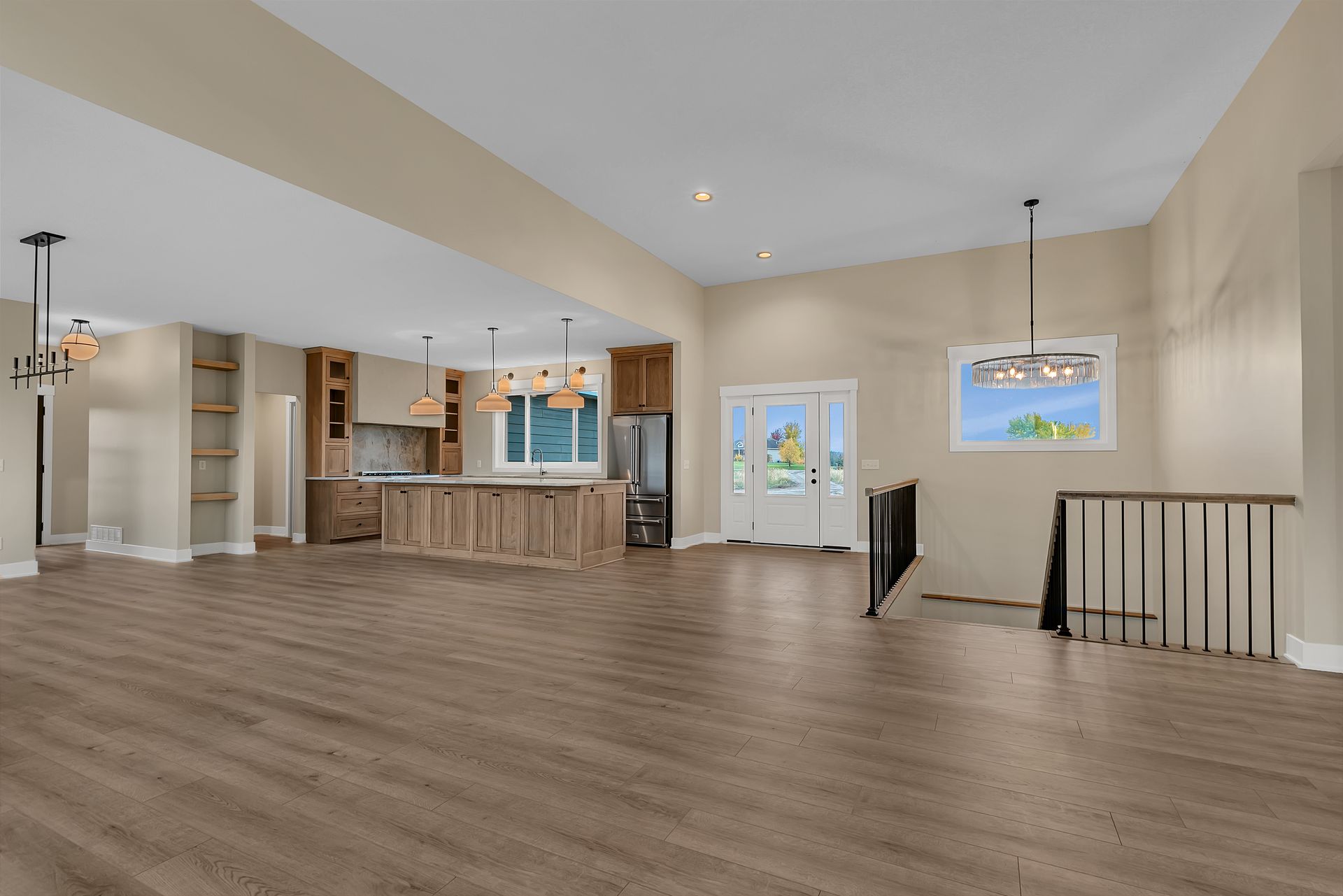 A large empty room with hardwood floors and a kitchen.