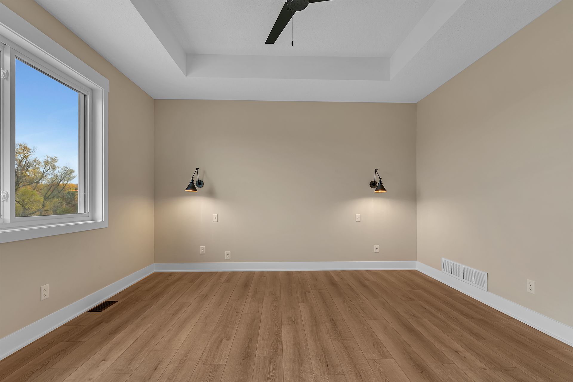 An empty room with hardwood floors and a ceiling fan.