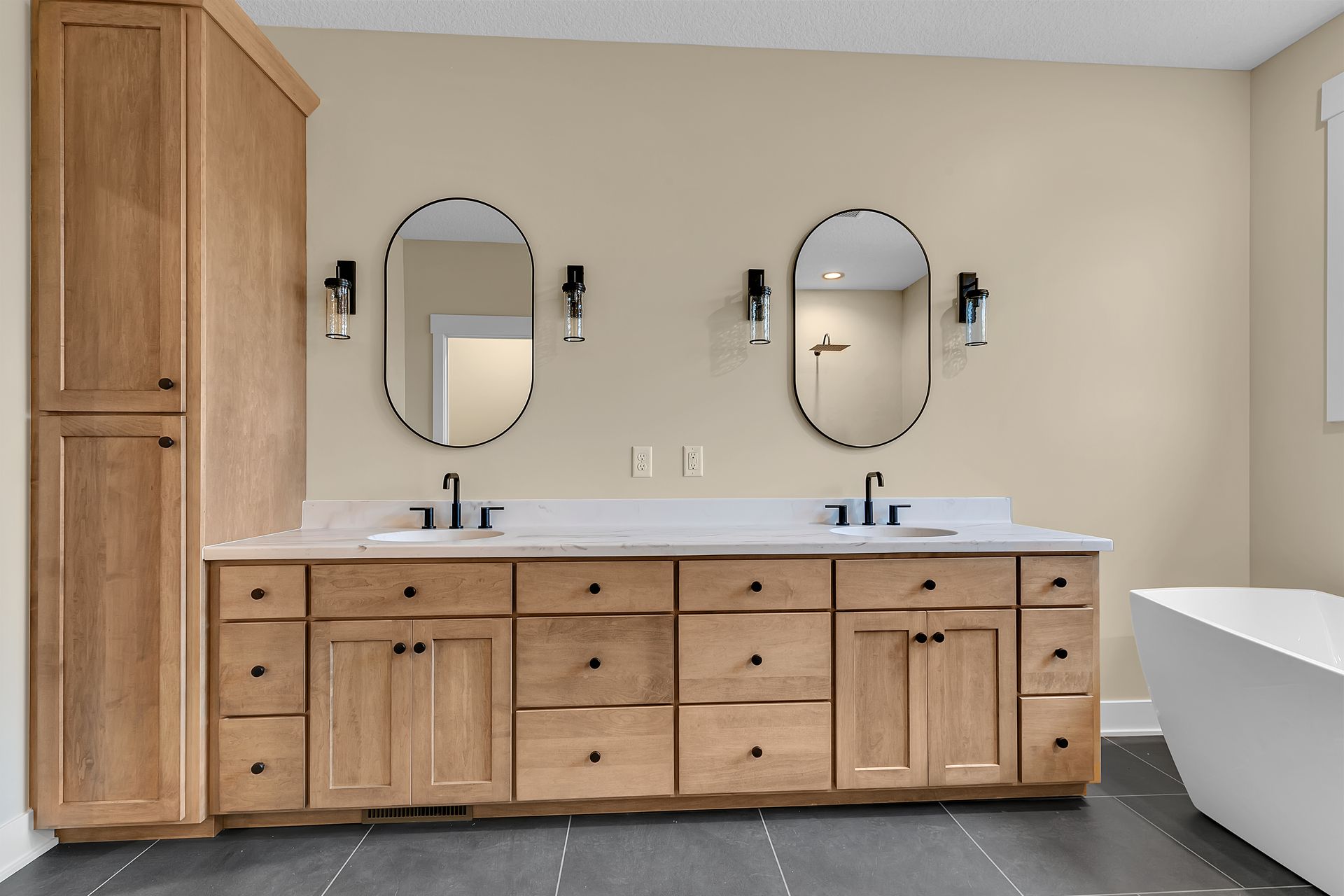 A bathroom with two sinks , two mirrors and a bathtub.