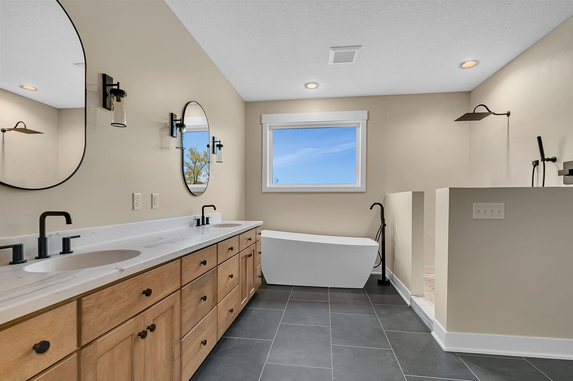 A bathroom with two sinks , a tub and a window