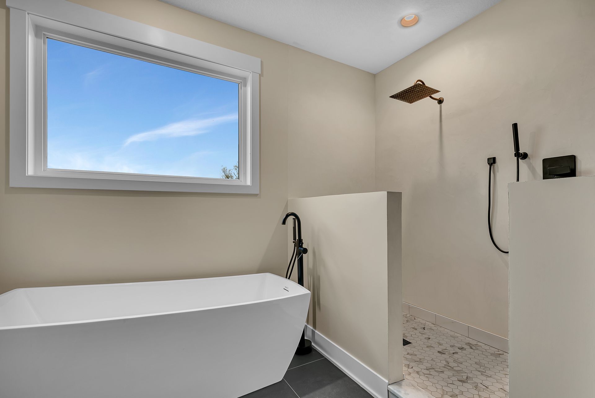 A bathroom with a tub , shower , and window.