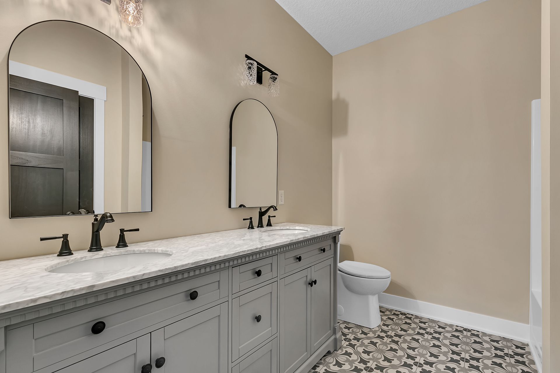 A bathroom with two sinks , a toilet and a mirror.