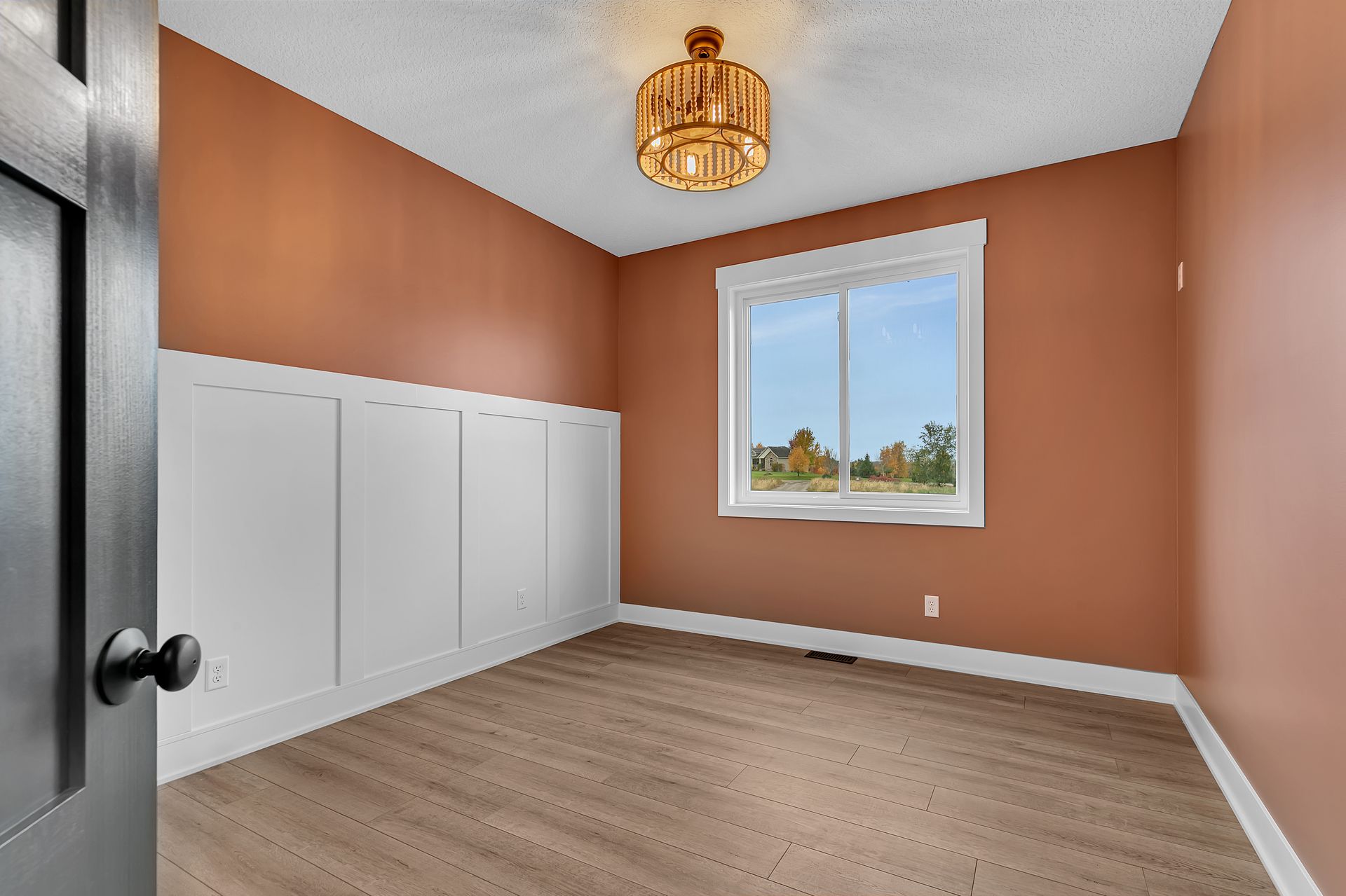An empty room with a window and a chandelier.