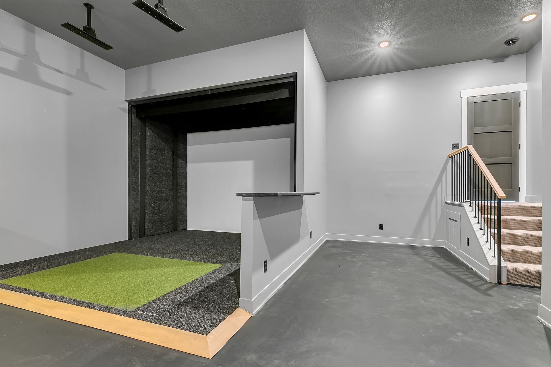 There is a golf simulator in the corner of the room.
