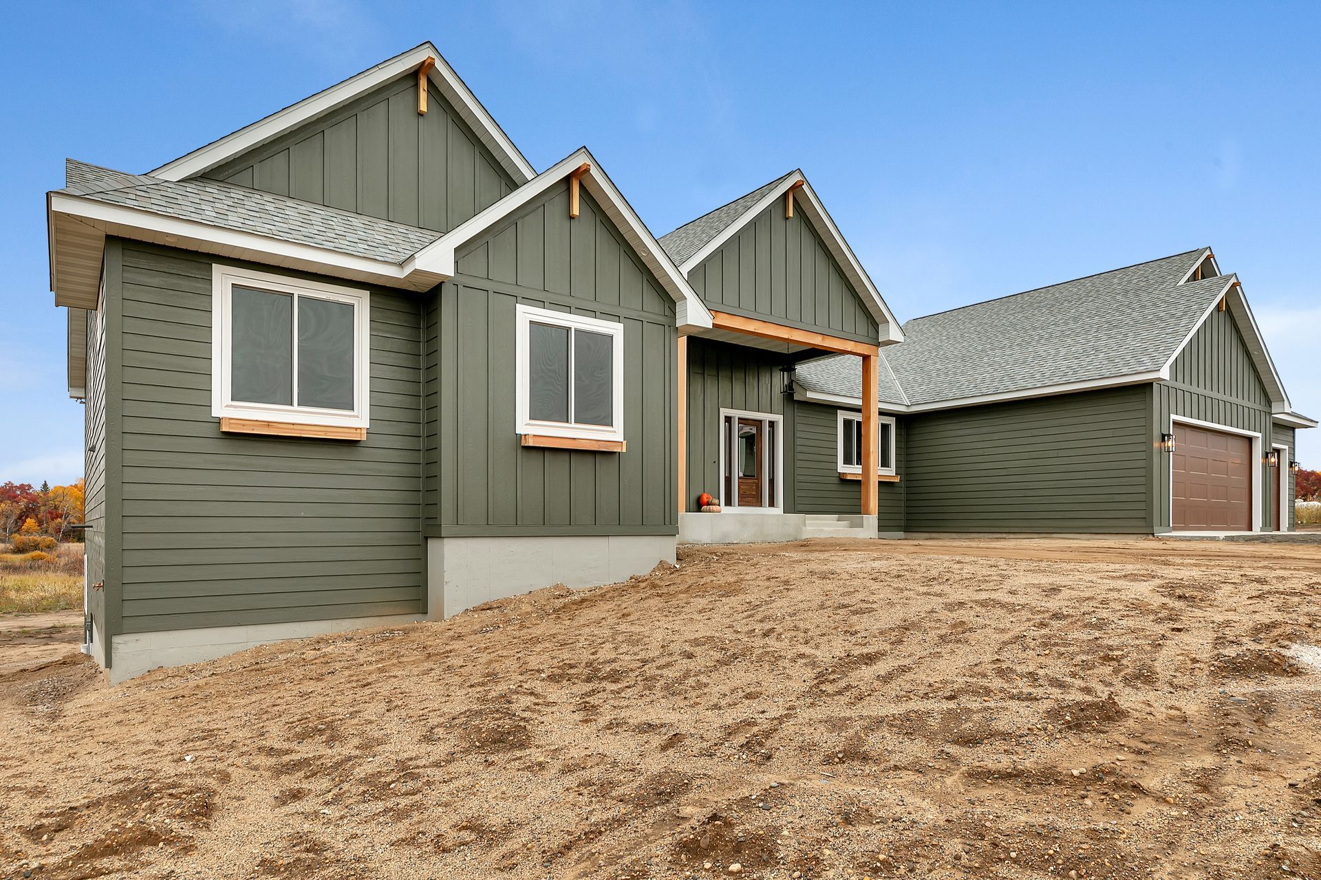 A house with a lot of windows is sitting on top of a dirt field.
