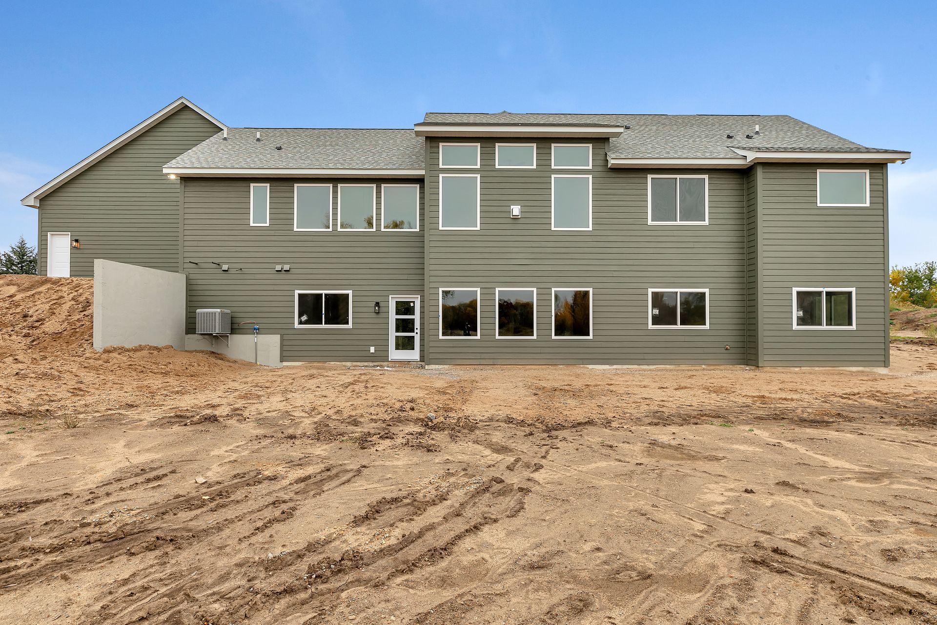 A large house with a lot of windows is sitting on top of a dirt field.