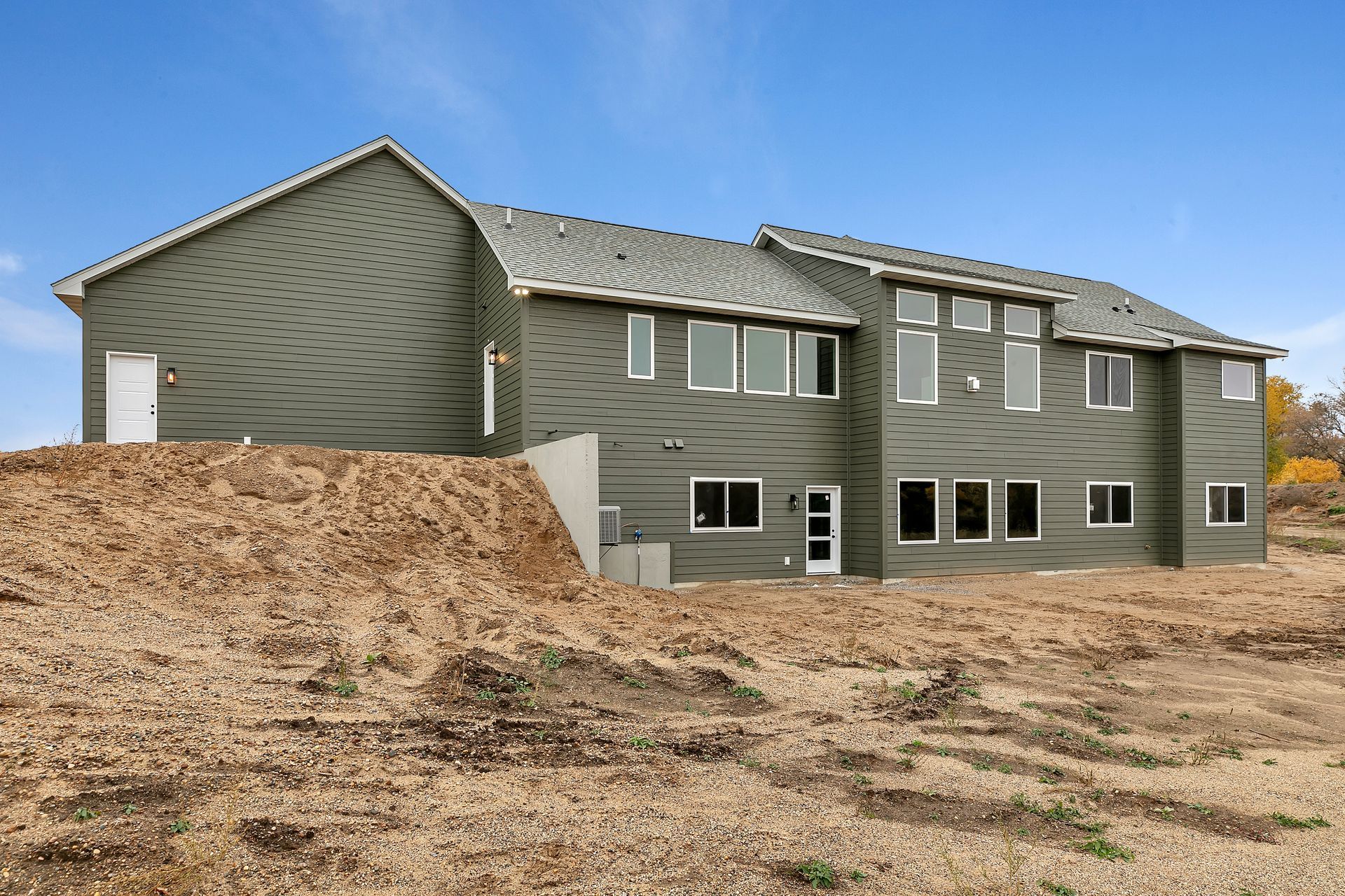 A large house is sitting on top of a dirt hill.