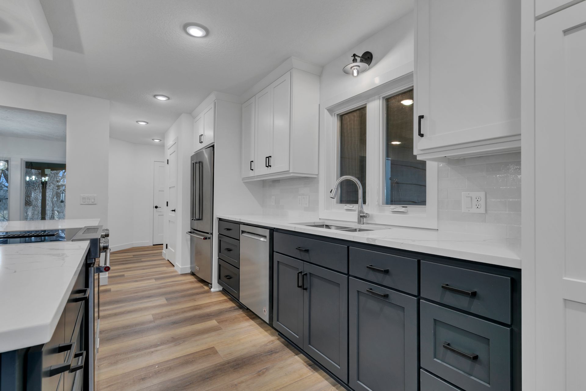 A kitchen with gray cabinets and white counter tops and stainless steel appliances.