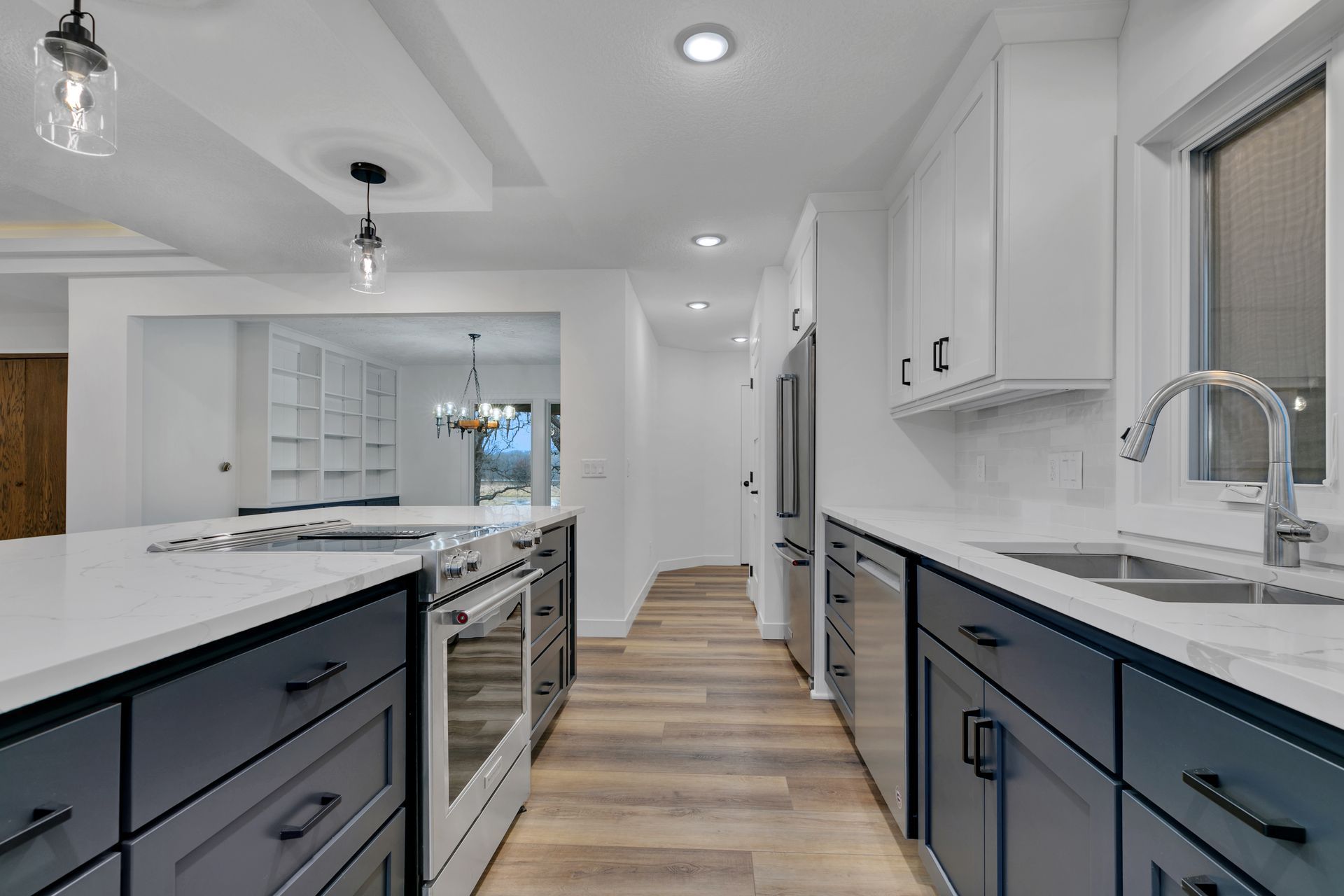 A kitchen with white cabinets and blue drawers and stainless steel appliances.