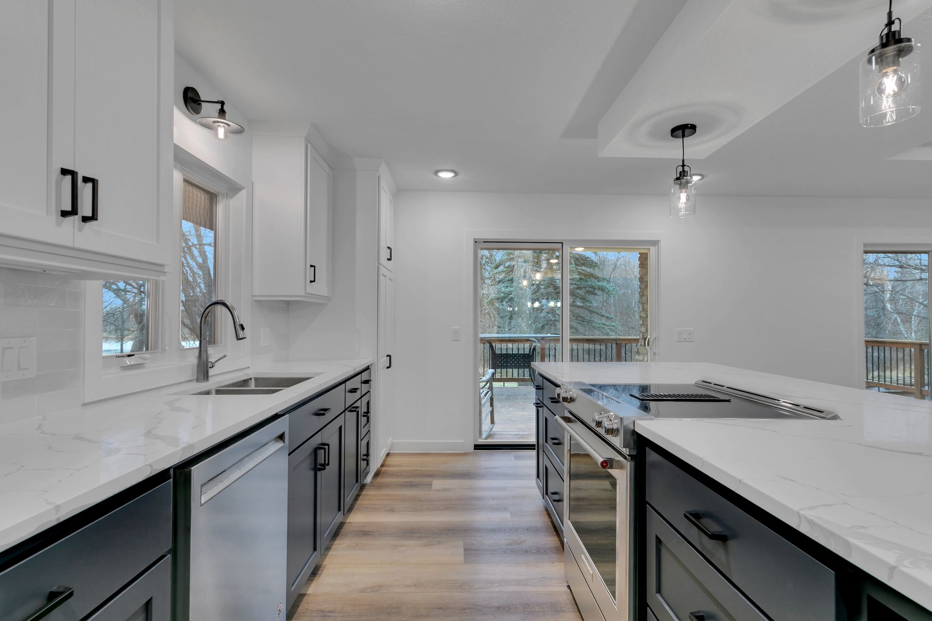 A kitchen with white cabinets and black drawers and stainless steel appliances.