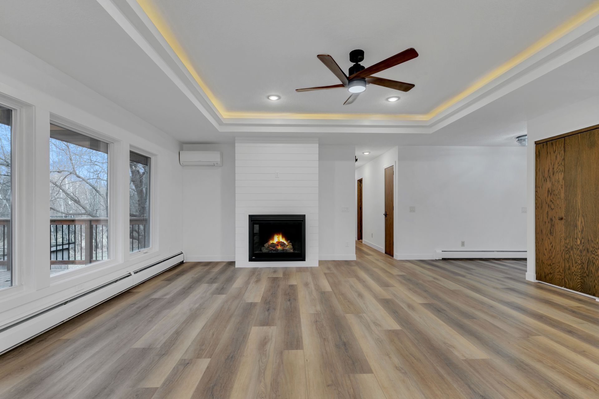 An empty living room with a fireplace and ceiling fan