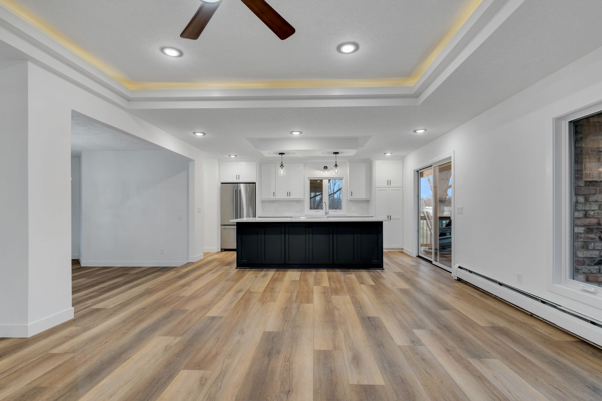 A large empty room with hardwood floors and a ceiling fan.