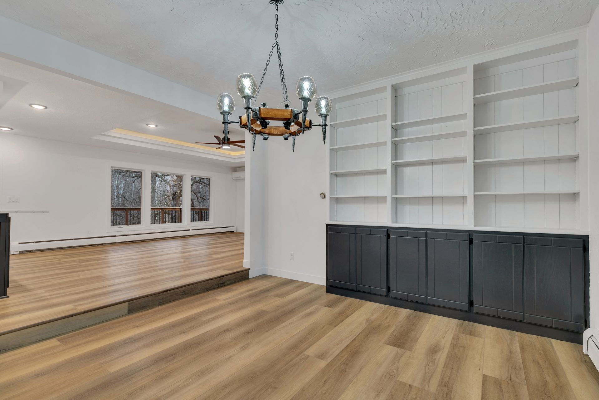 A living room with hardwood floors , a chandelier , and built in shelves.