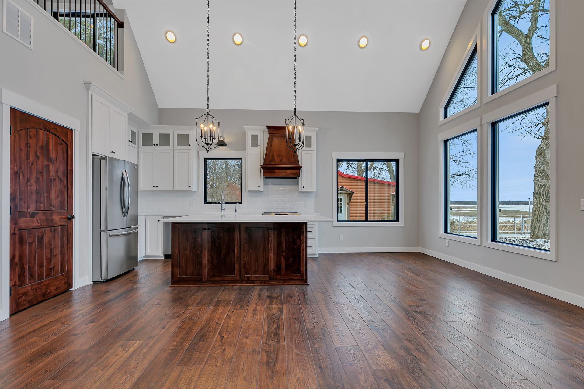 A large empty room with hardwood floors and a kitchen.