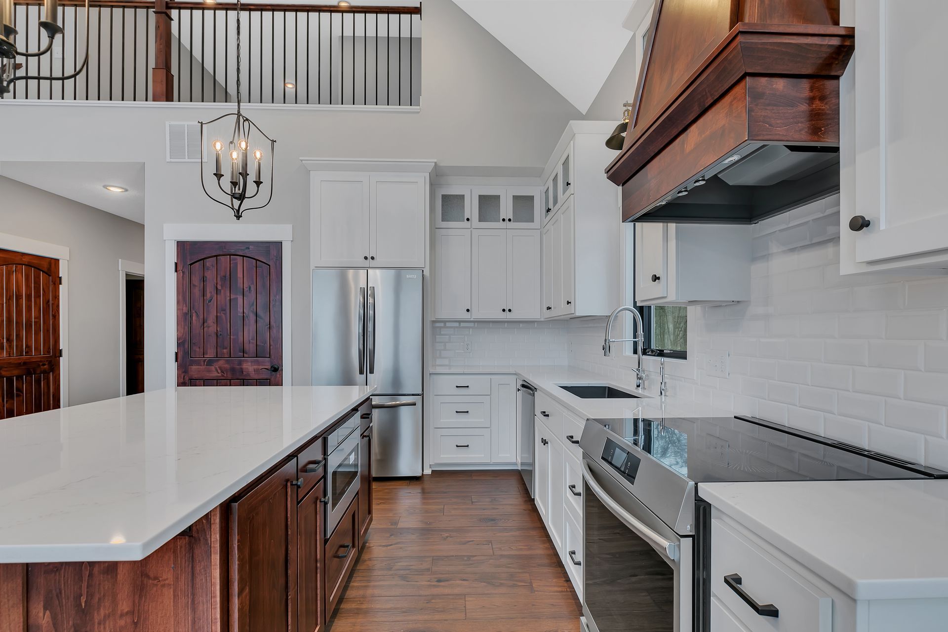 A kitchen with white cabinets , stainless steel appliances , and a large island.
