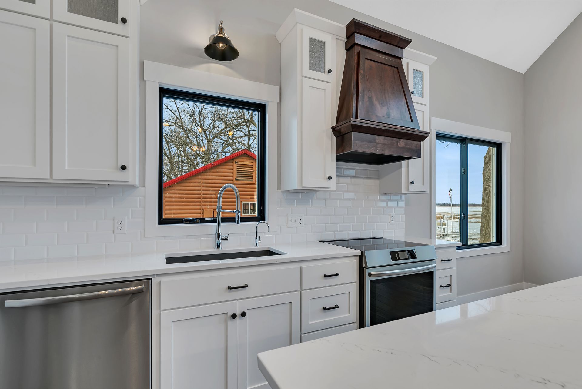 A kitchen with white cabinets , stainless steel appliances , a sink , and a window.