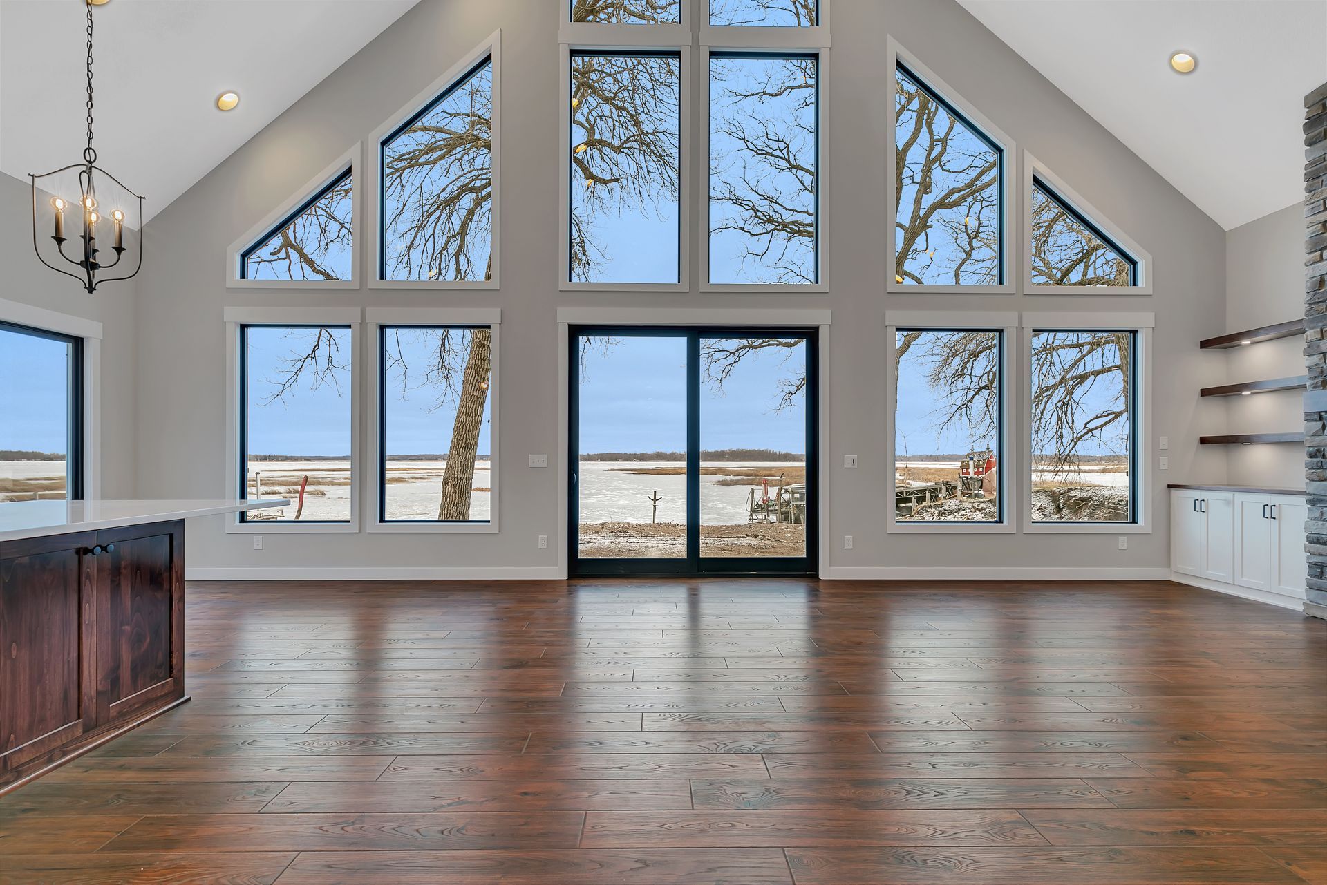 An empty living room with a lot of windows and hardwood floors.