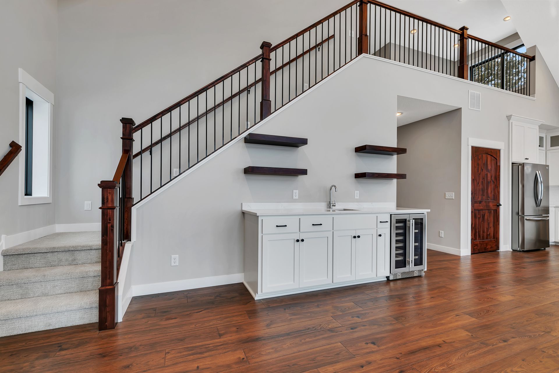 A kitchen with a sink , refrigerator , and stairs leading up to the second floor.