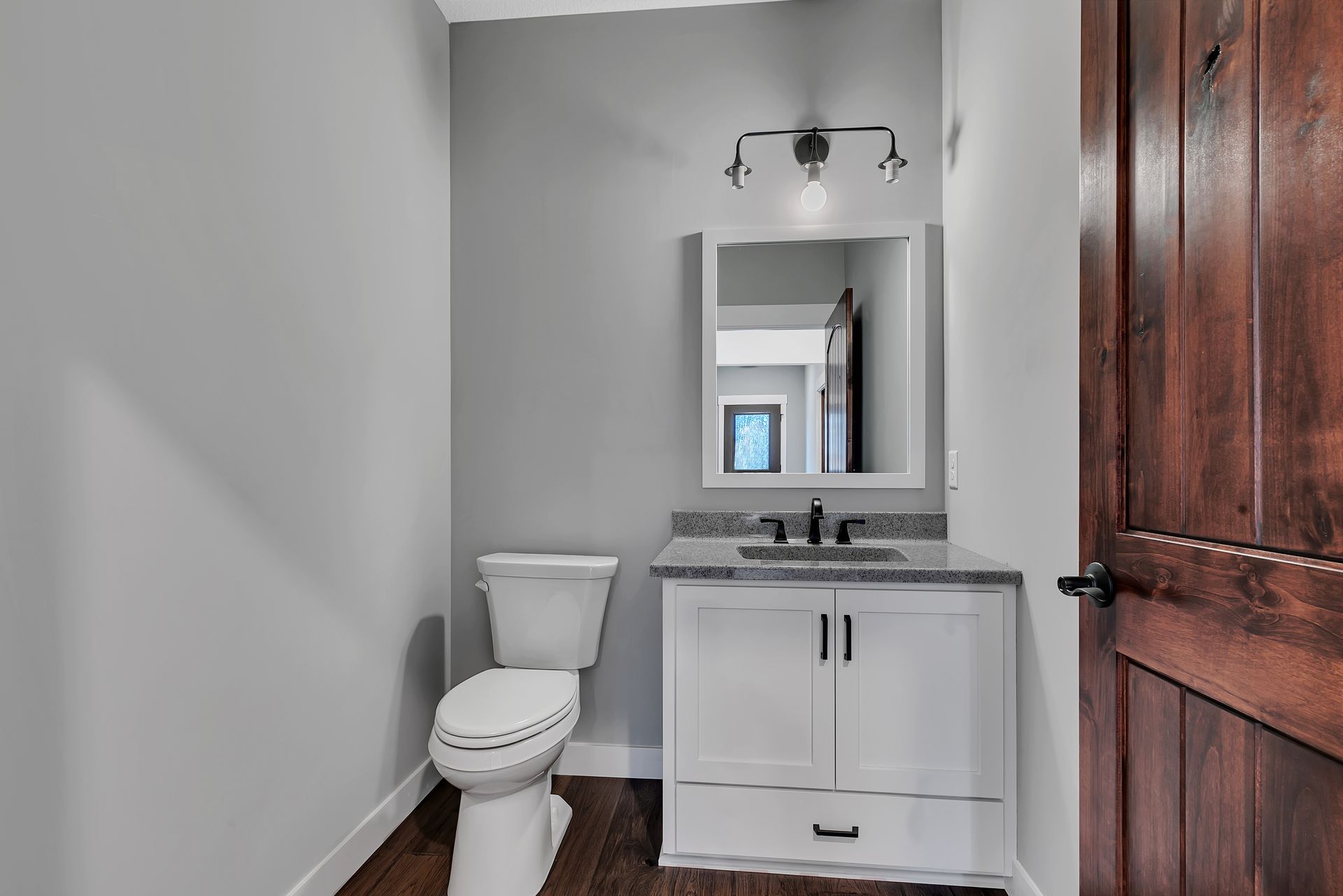 A bathroom with a toilet , sink and mirror.