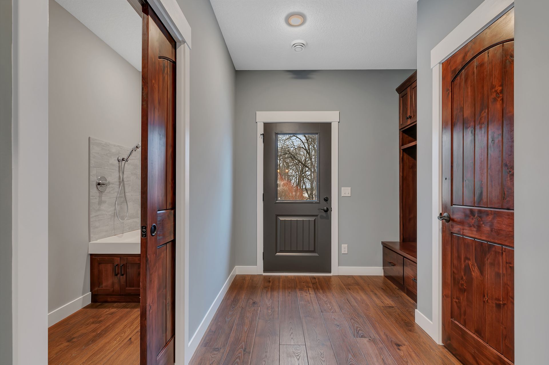 A hallway in a house with hardwood floors and a black door.