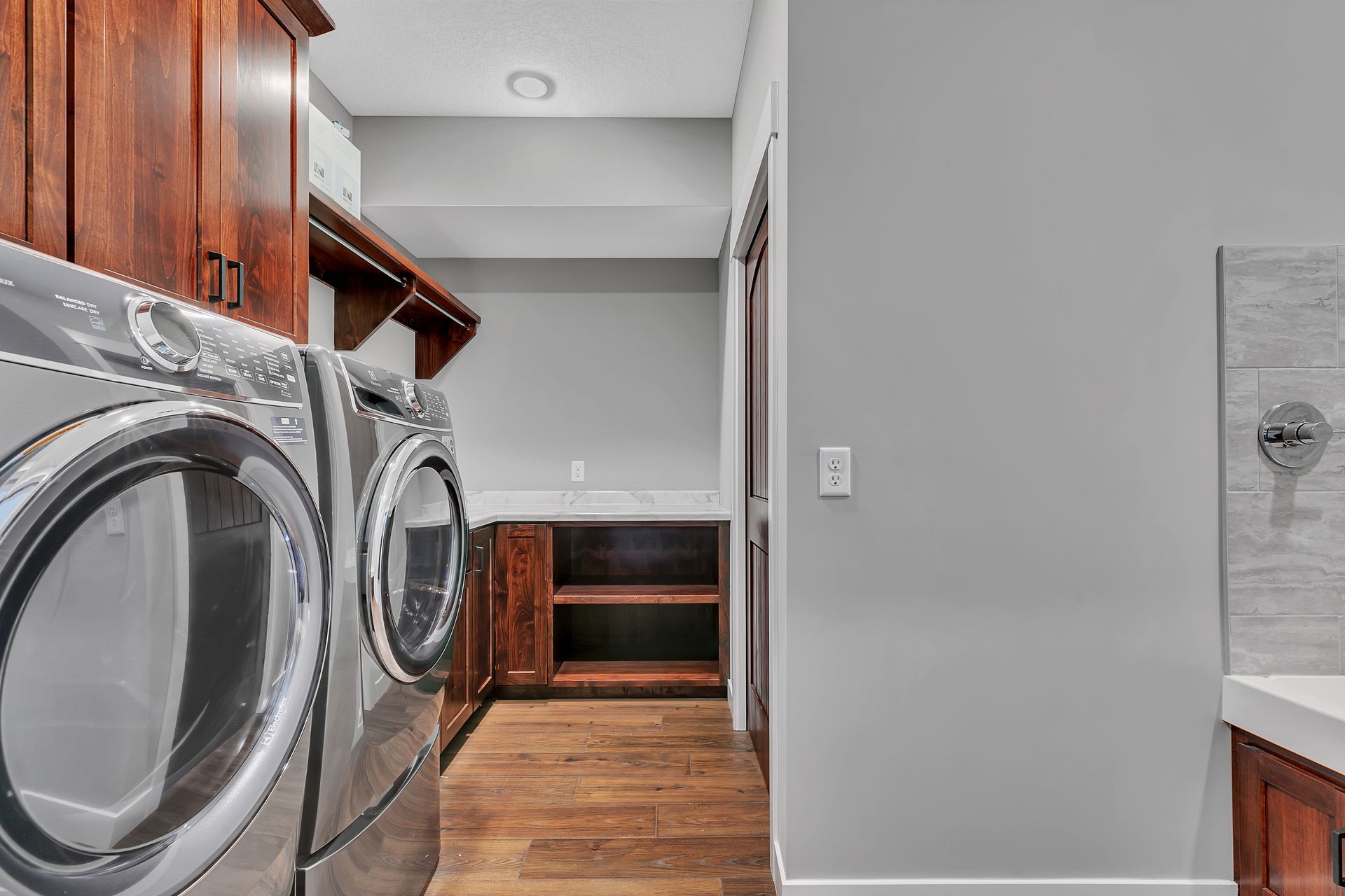 A laundry room with a washer and dryer and wooden cabinets.
