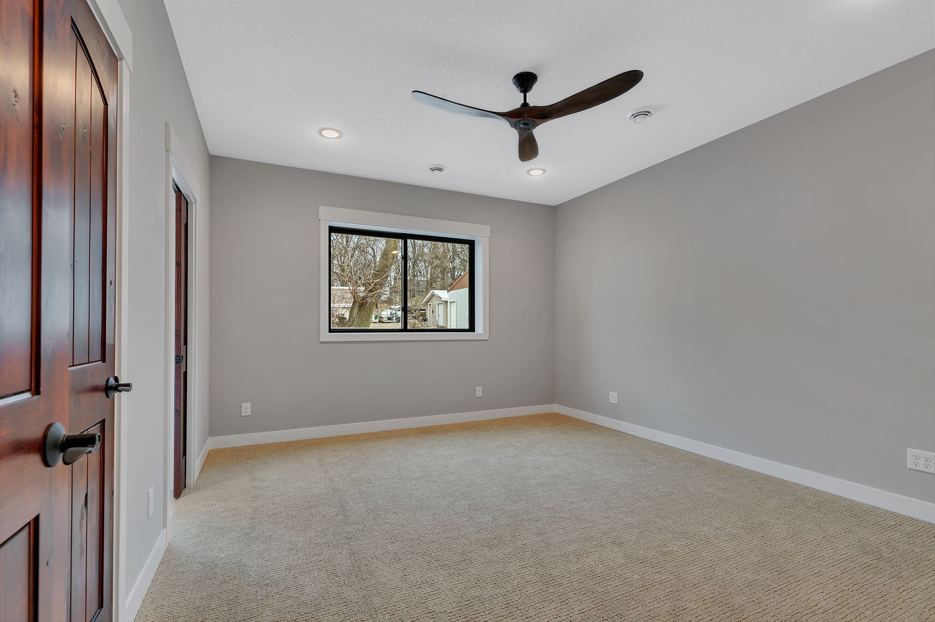 An empty bedroom with a ceiling fan and a window.