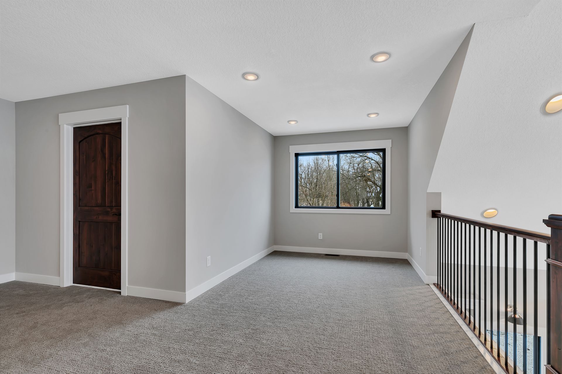 An empty room with a carpeted floor and a window.