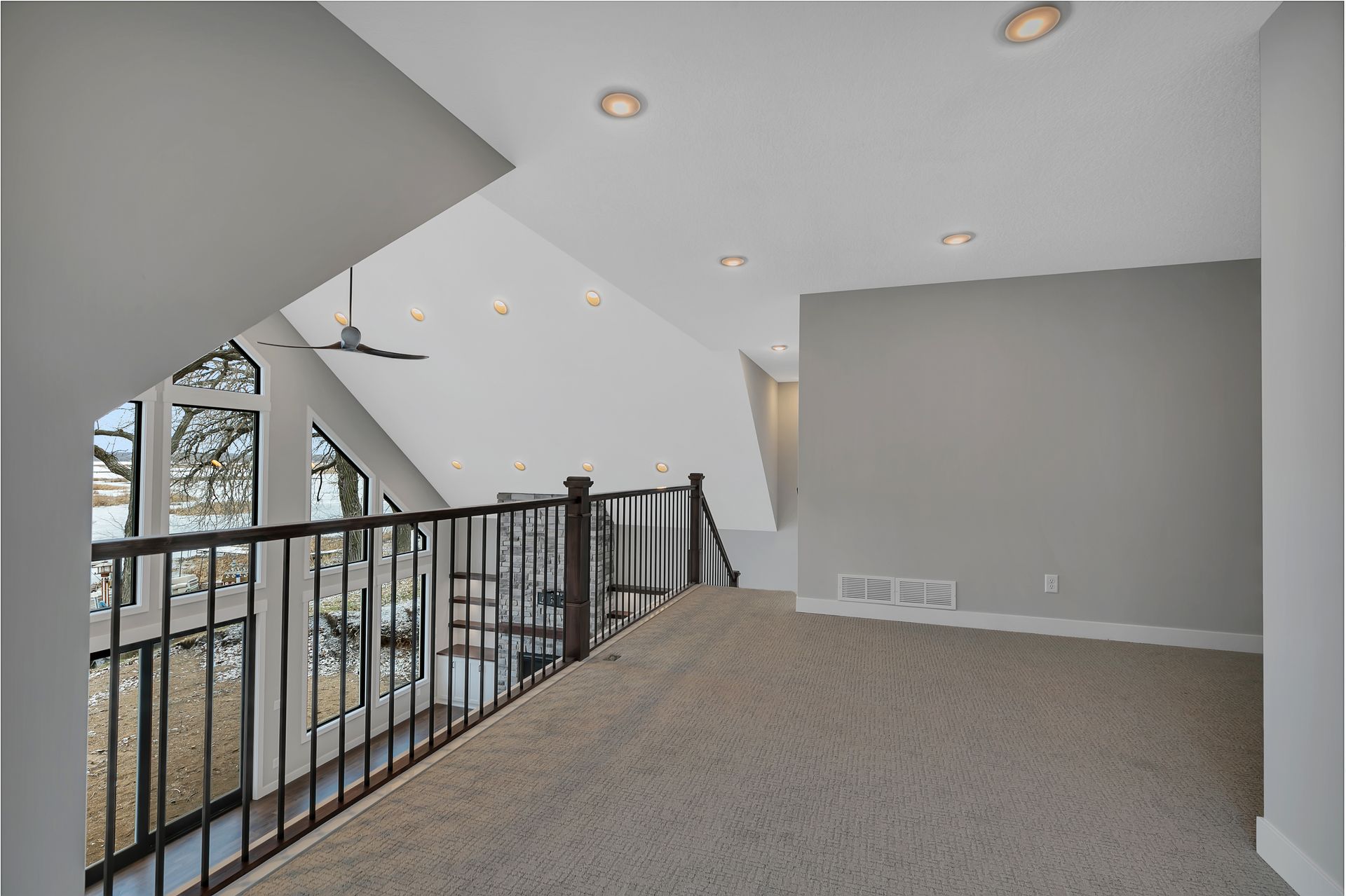 An empty room with a balcony and stairs in a house.