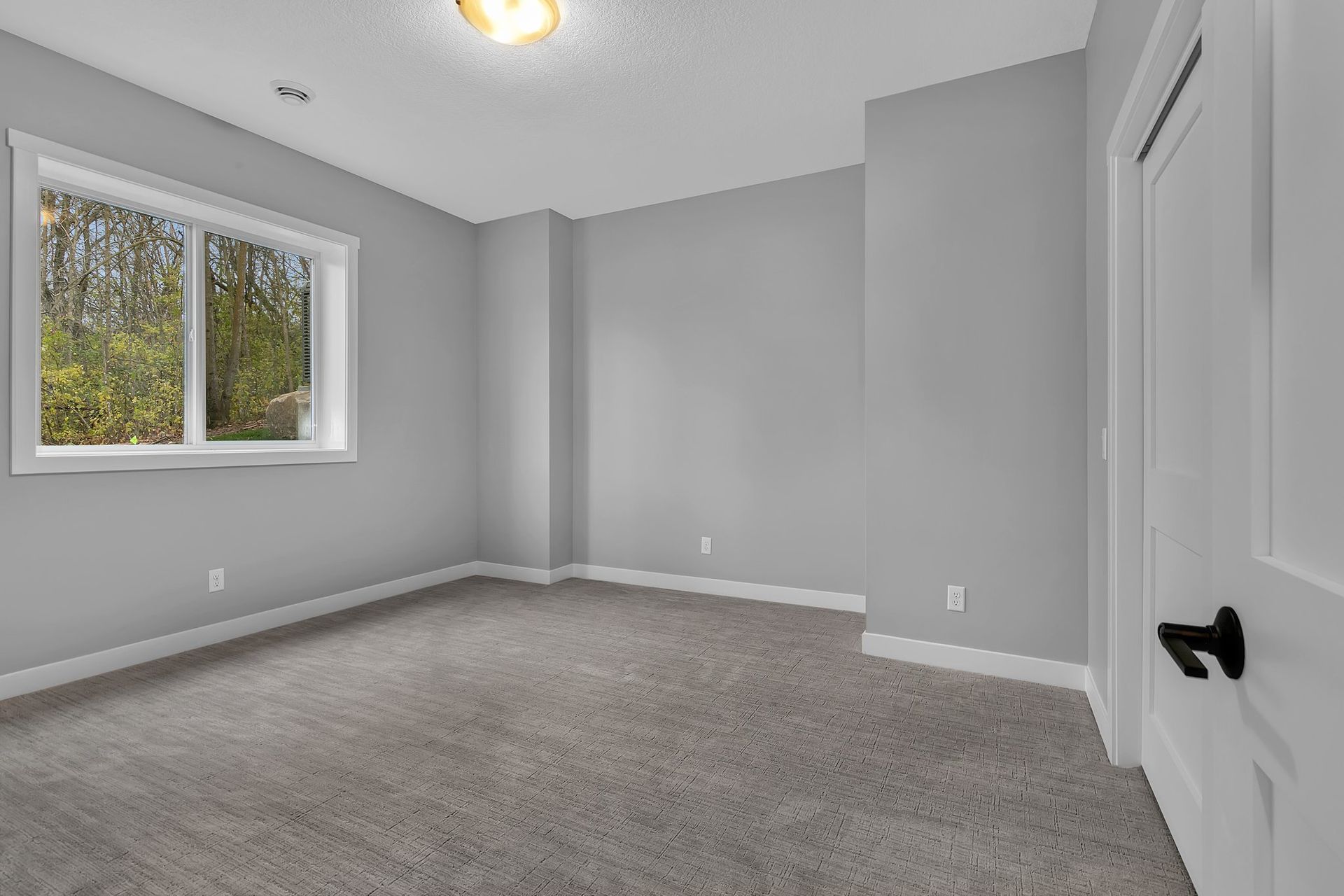 An empty bedroom with gray walls and a window.