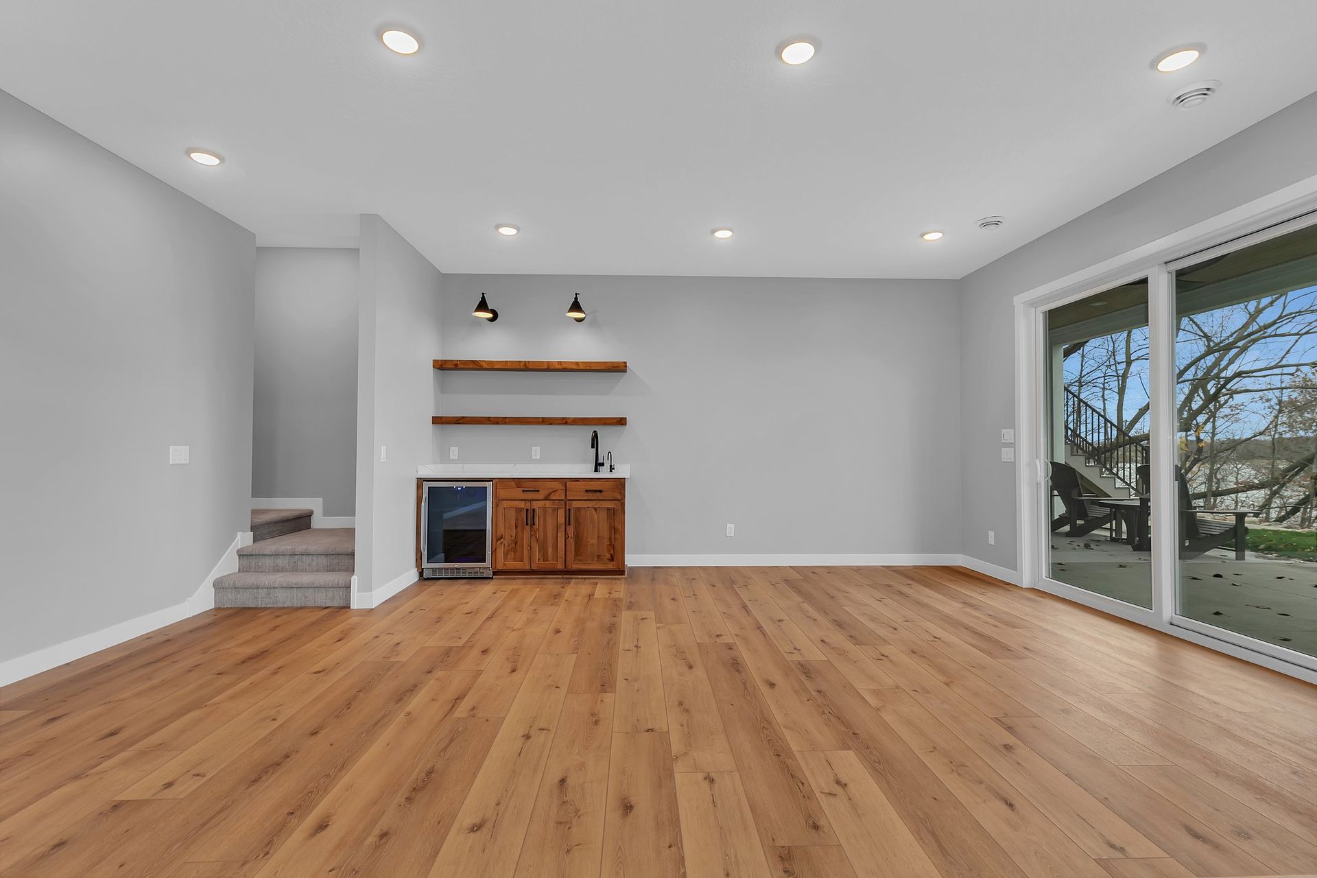 An empty living room with hardwood floors and a sliding glass door.