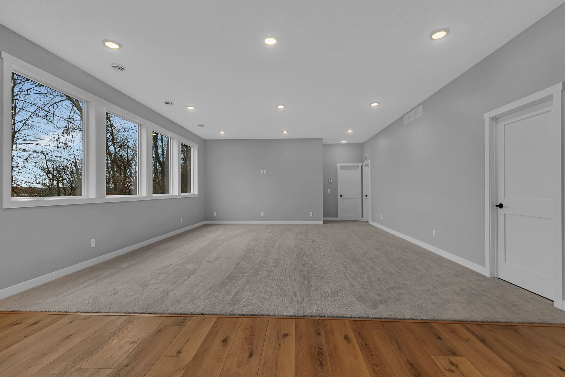 An empty room with a lot of windows and hardwood floors.