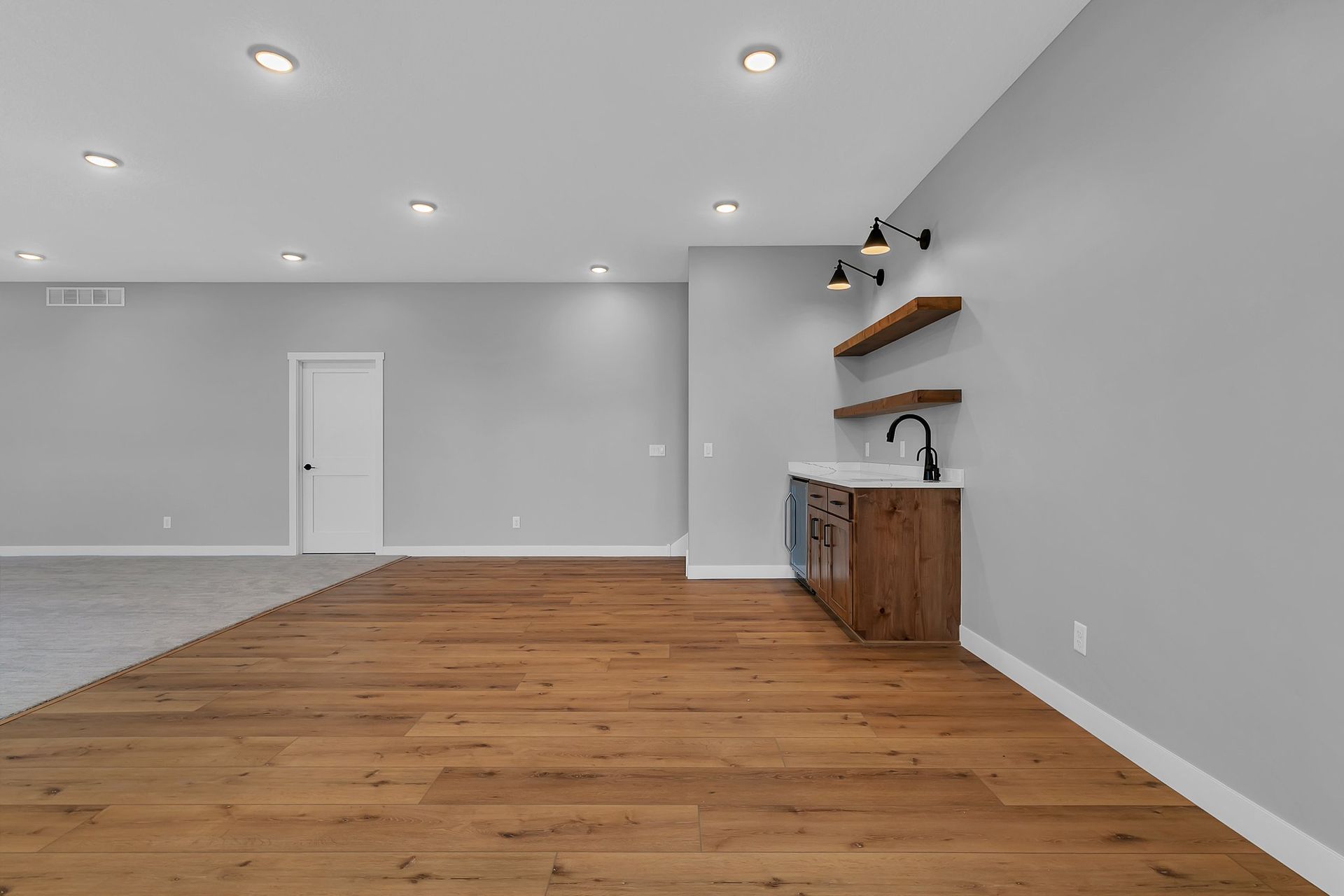 A large empty room with hardwood floors and a sink.