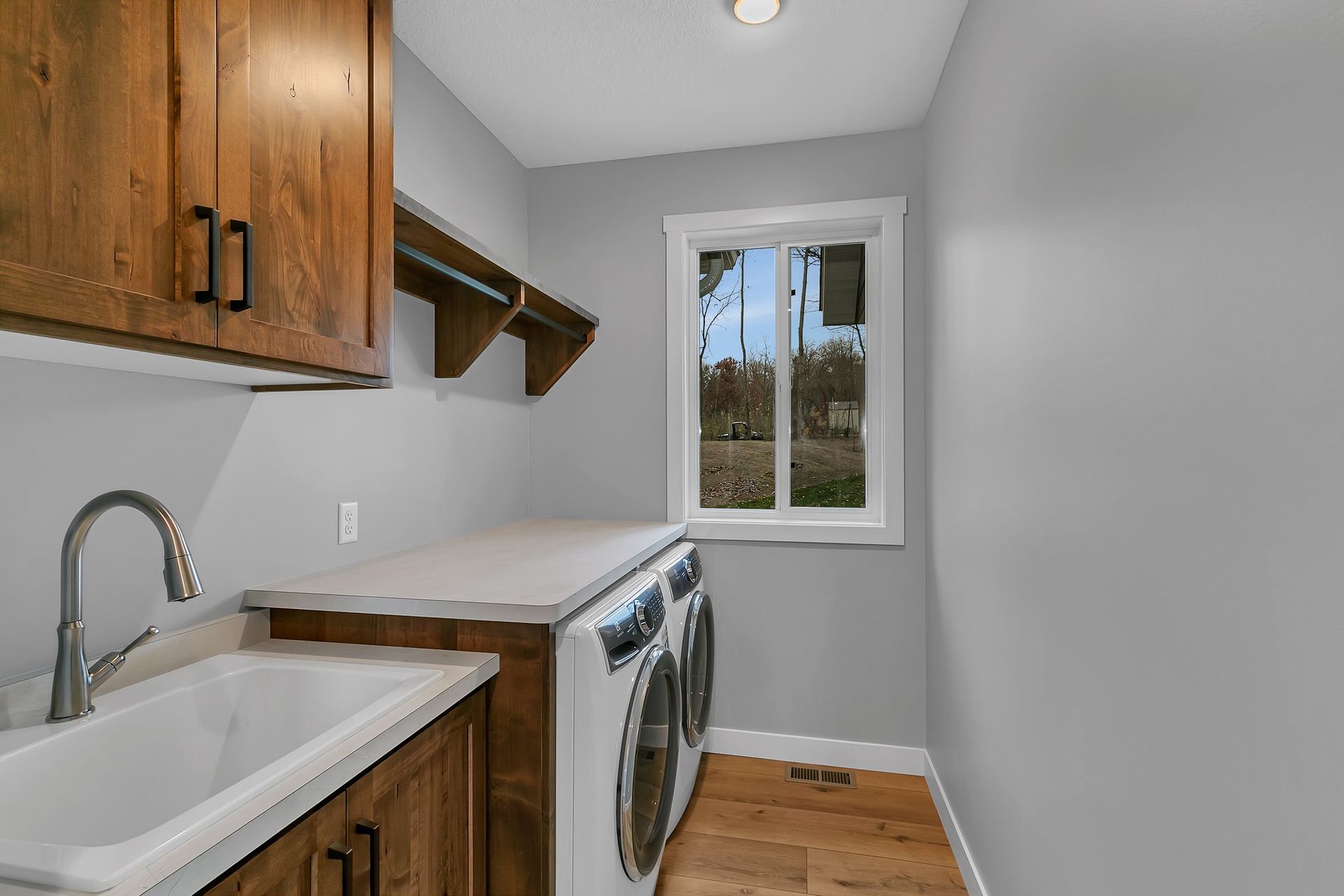 A laundry room with a washer and dryer , sink , and window.