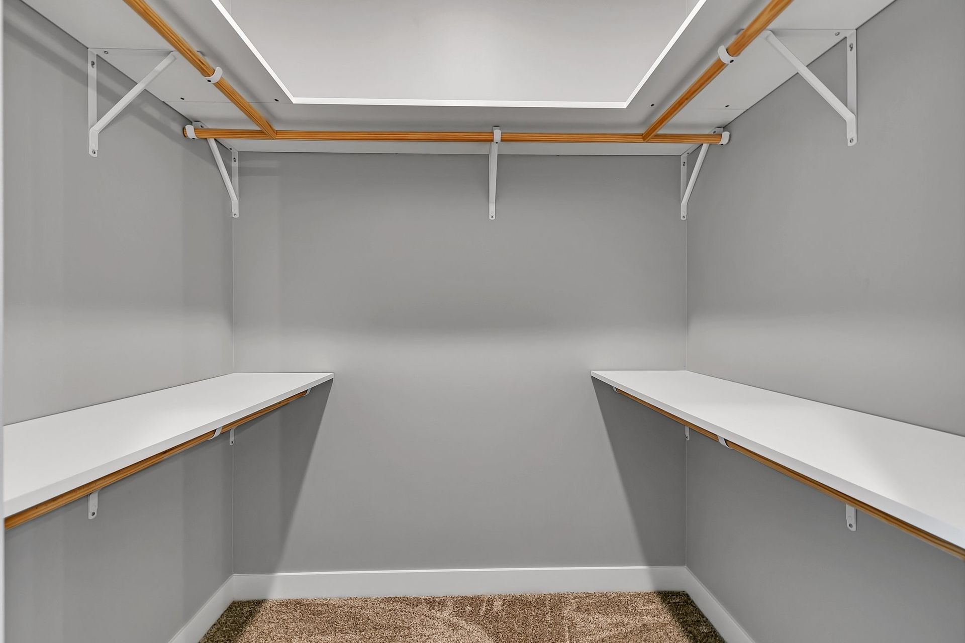 An empty walk in closet with shelves and a rug.