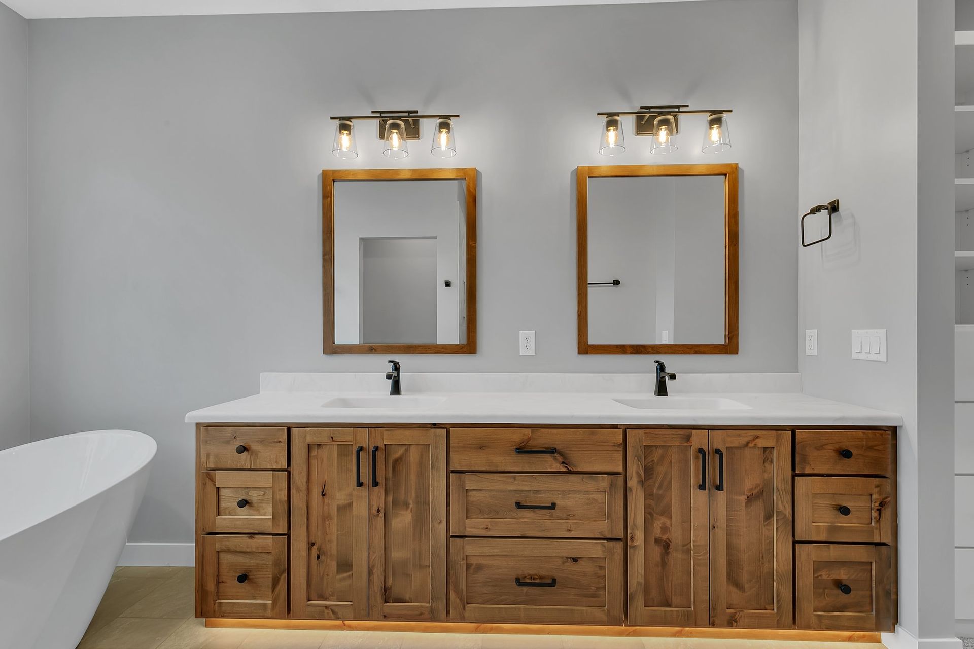 A bathroom with two sinks , two mirrors , and a bathtub.