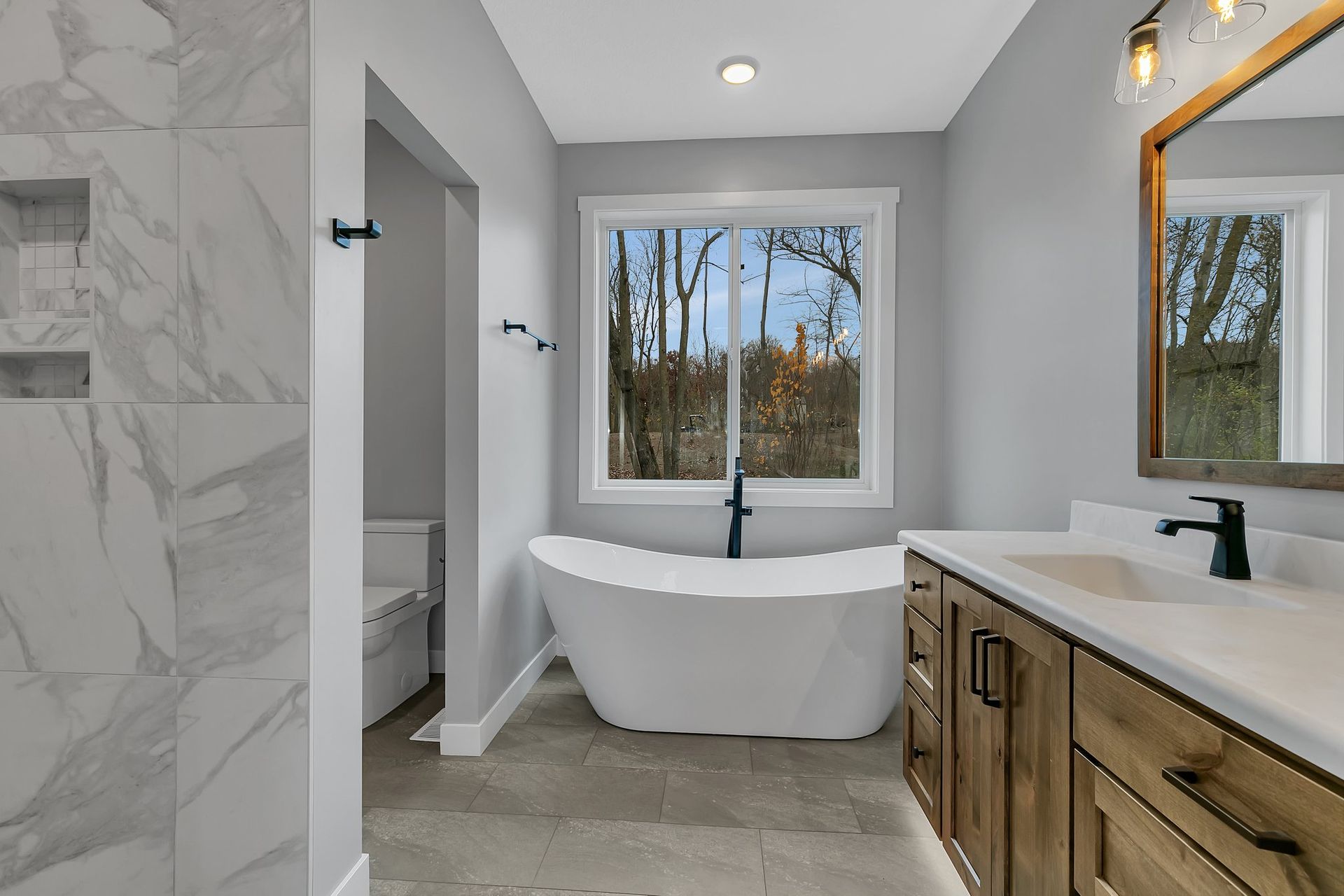 A bathroom with a tub , sink , and mirror.