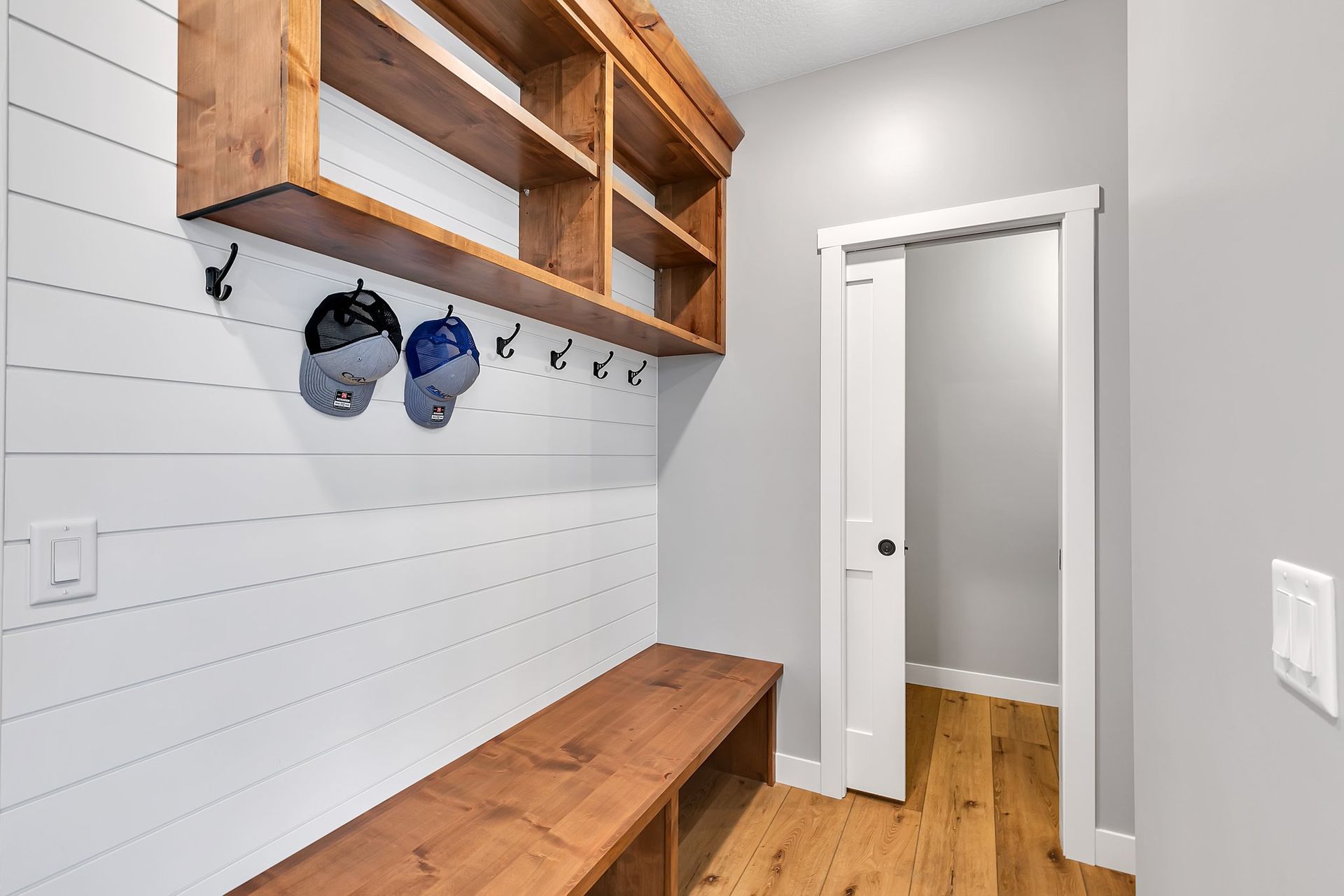A hallway with a bench and hooks on the wall.