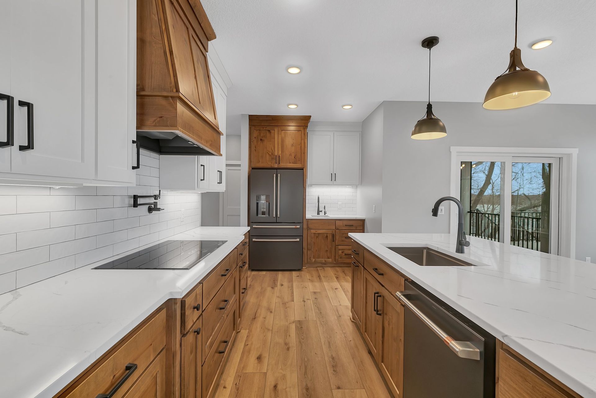A kitchen with wooden cabinets , white counter tops , stainless steel appliances and a large island.