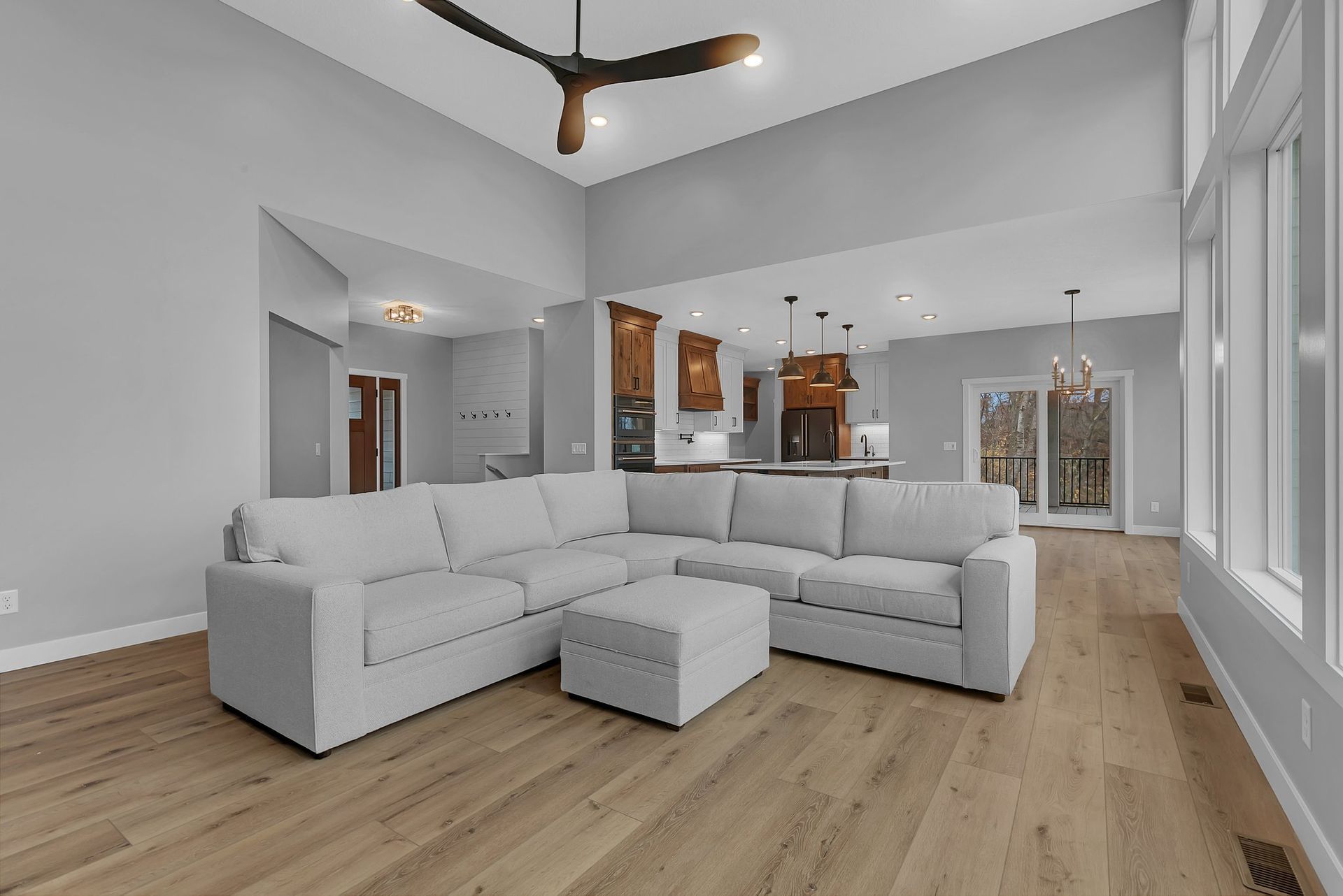 A living room with a white sectional couch and a ceiling fan.