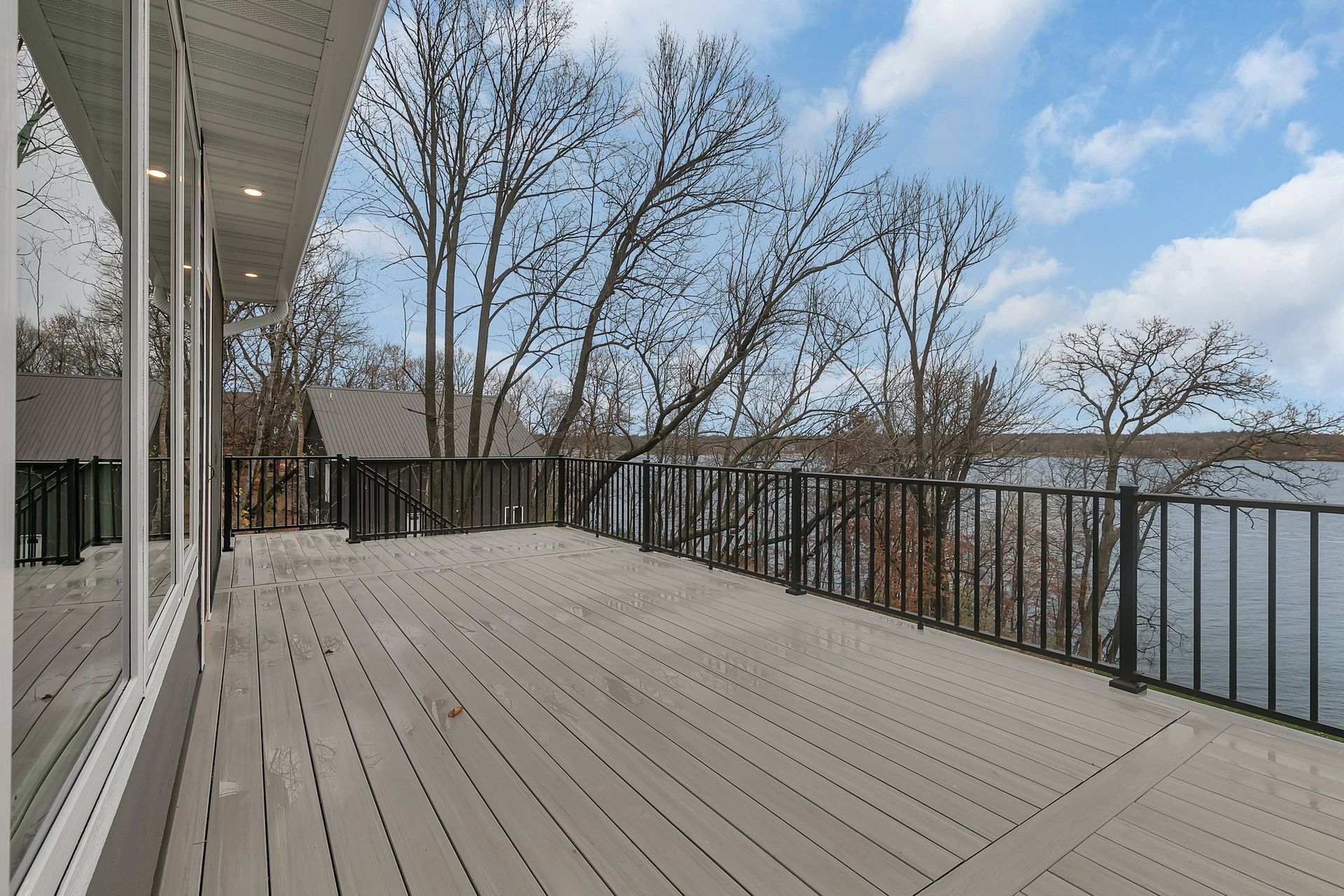 A large deck with a railing overlooking a lake