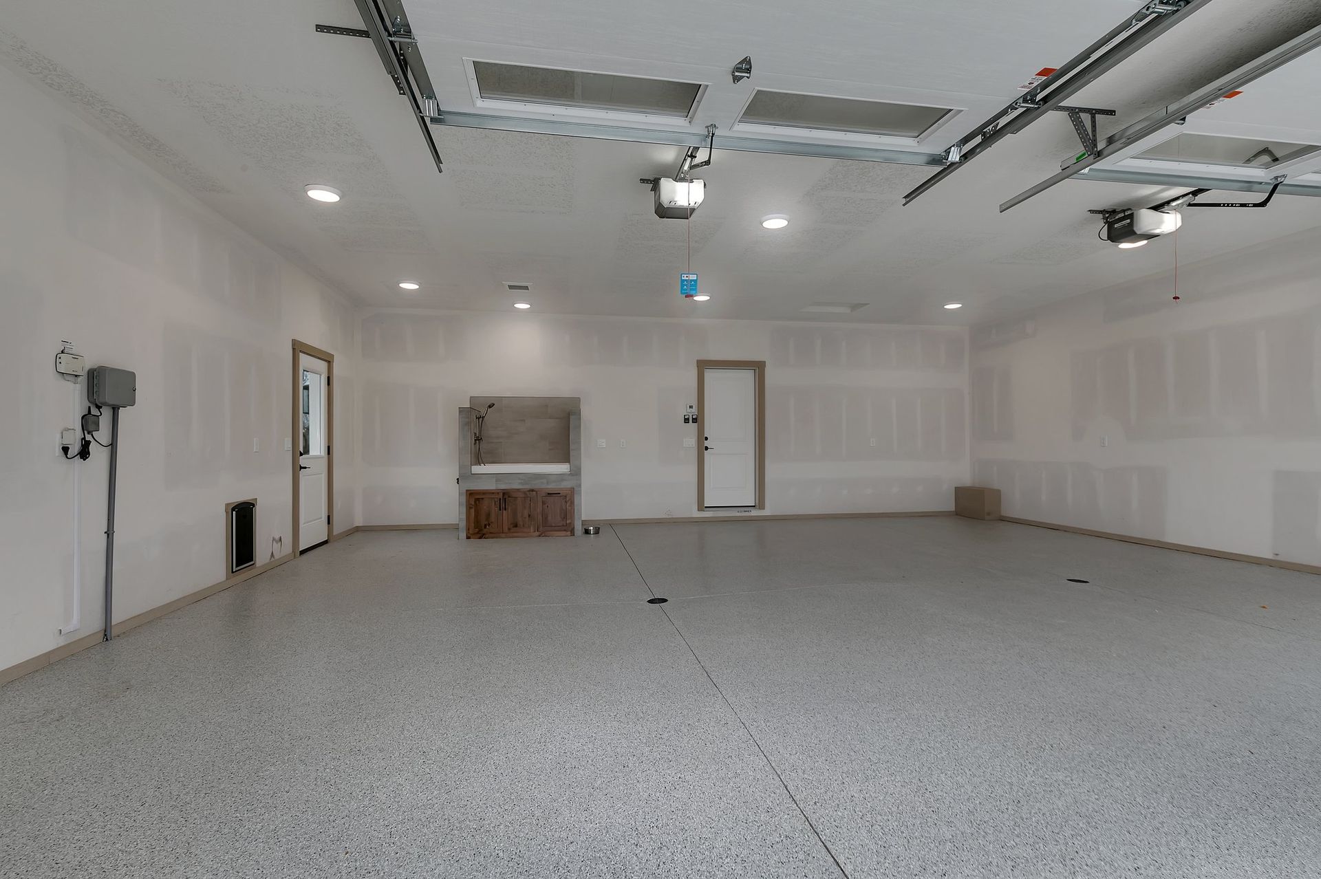 A large empty garage with a gray floor and white walls.