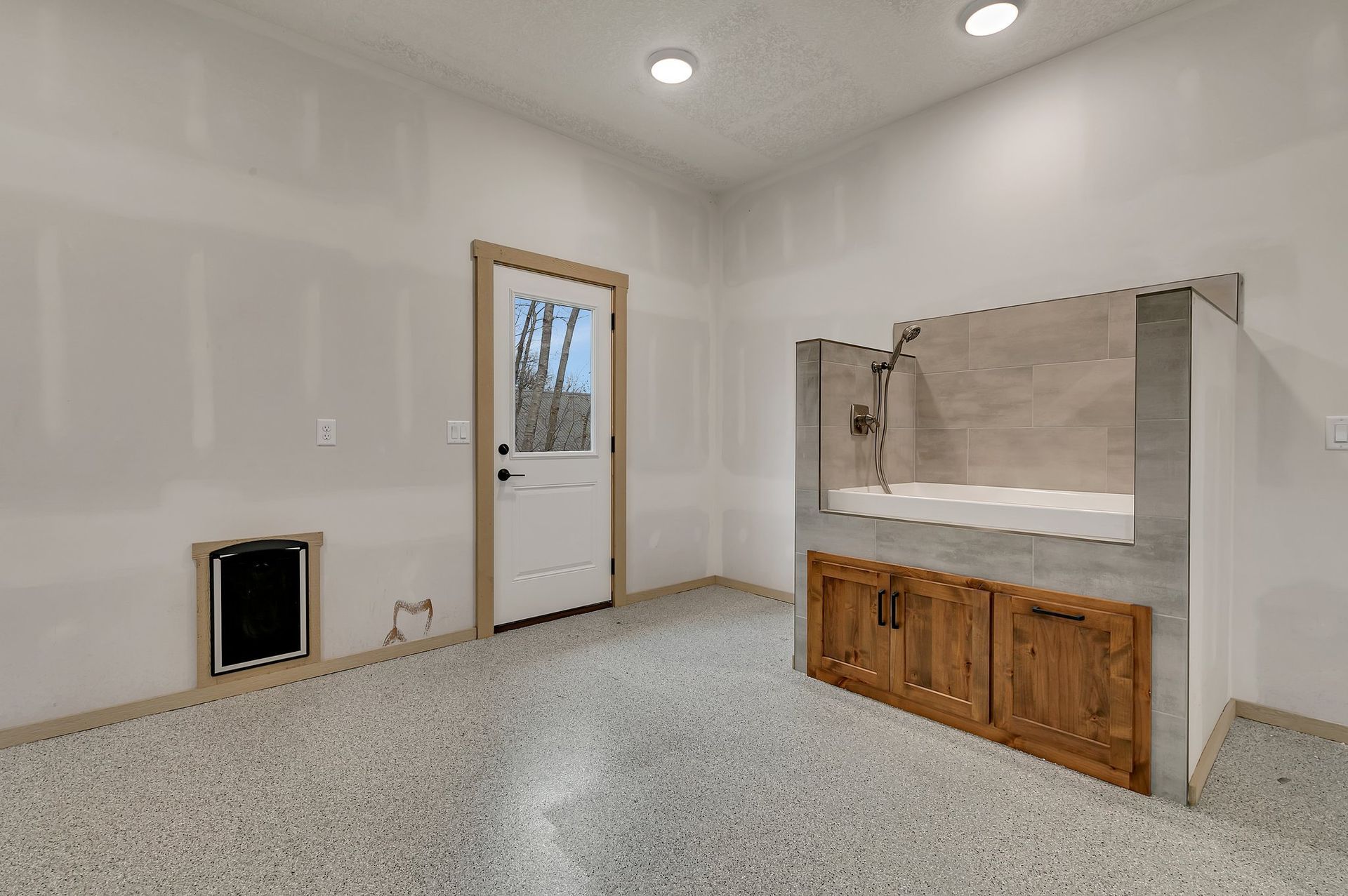 A room with a dog bathtub and a door.