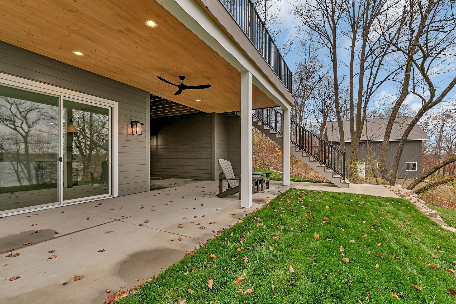 A large patio with a ceiling fan and chairs in the backyard of a house.