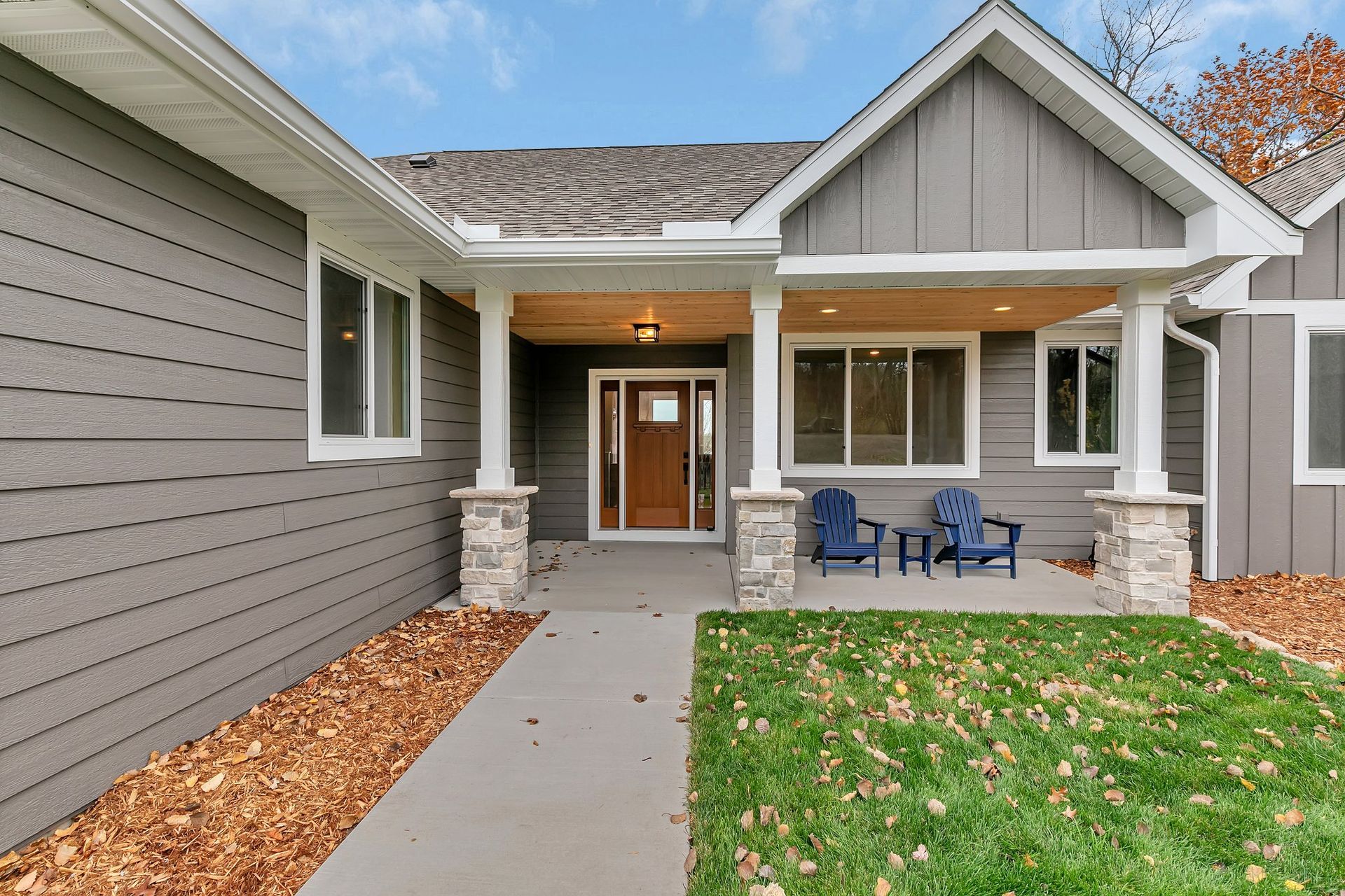 A gray house with a porch and chairs in front of it