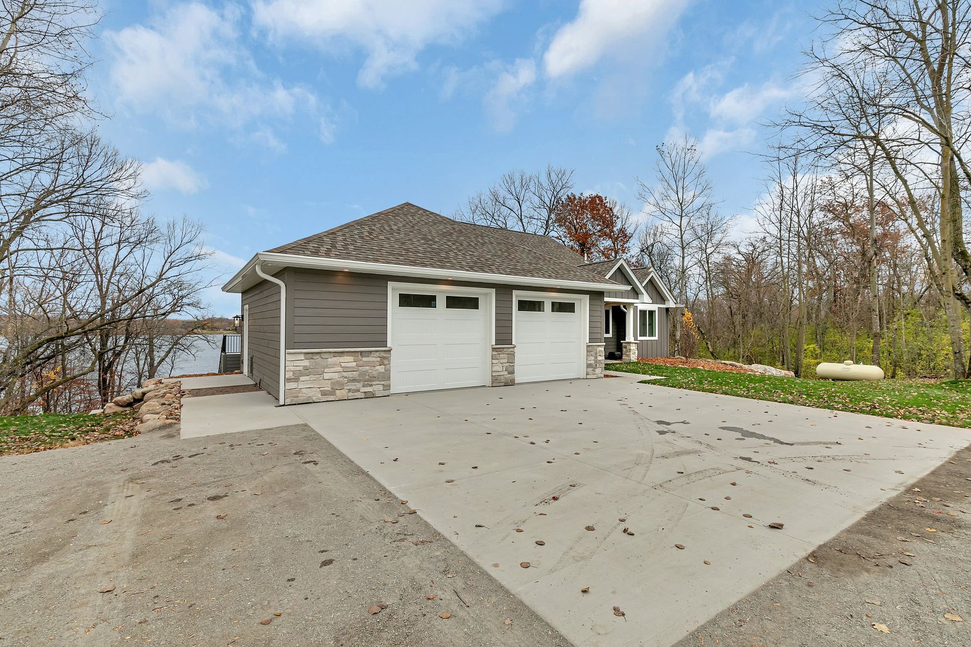A house with a garage and a driveway next to a lake.