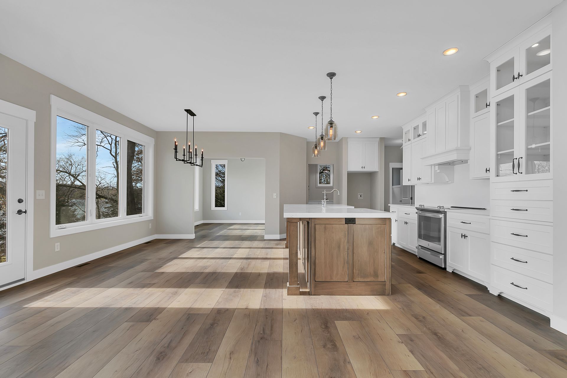 An empty kitchen with hardwood floors and white cabinets.