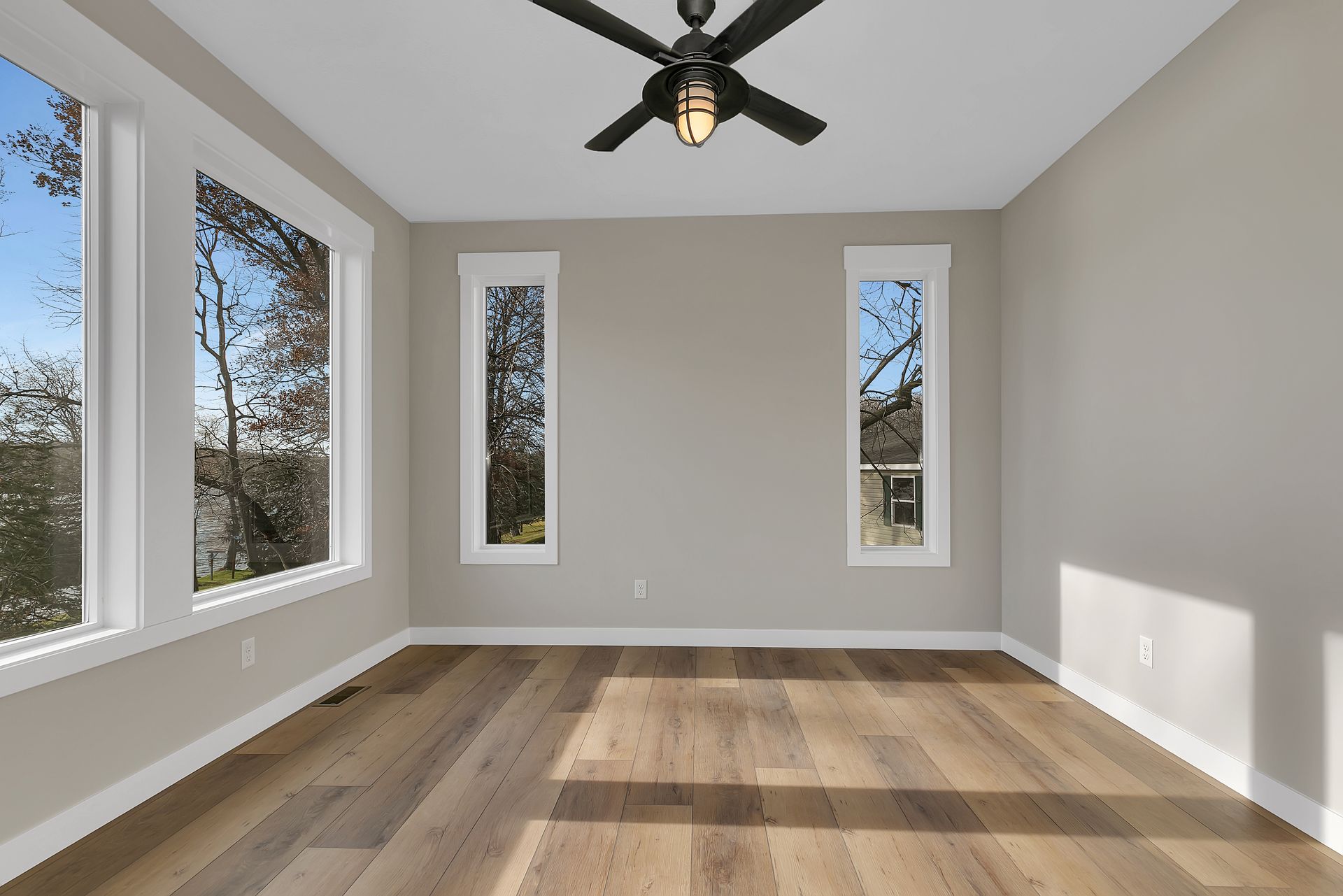 An empty room with hardwood floors and a ceiling fan
