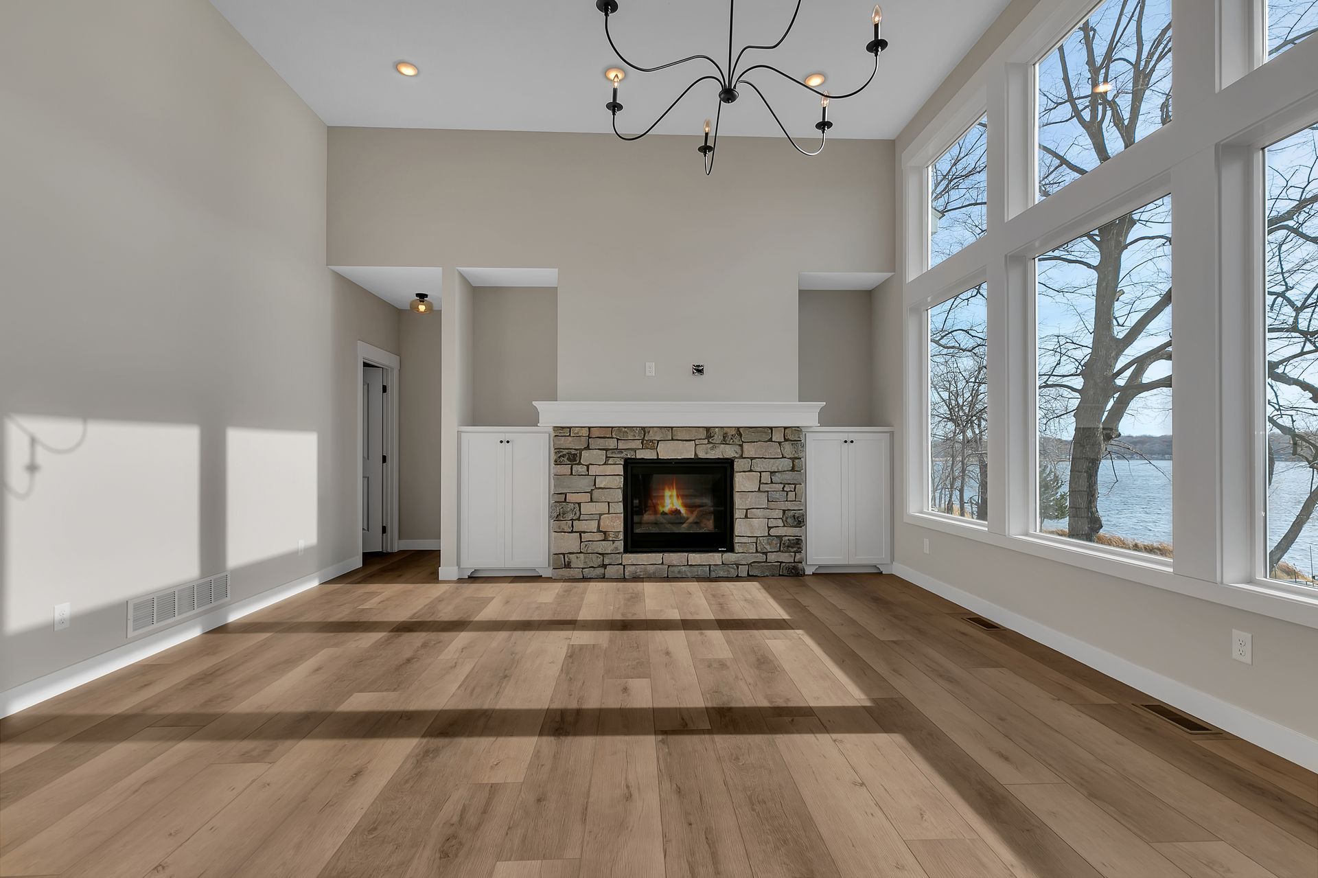An empty living room with a fireplace and lots of windows